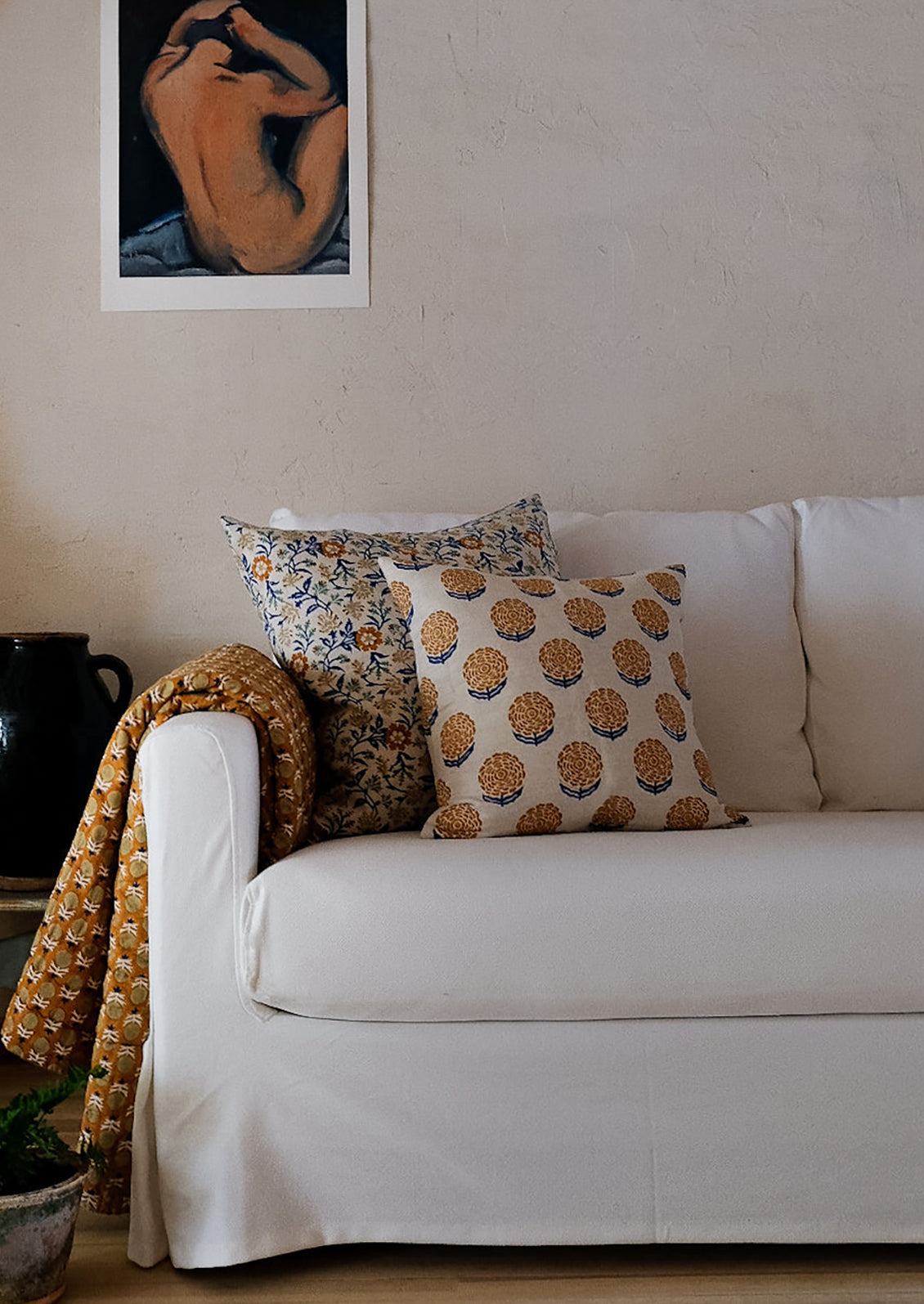 A block printed pillow with orange and blue marigold pattern.