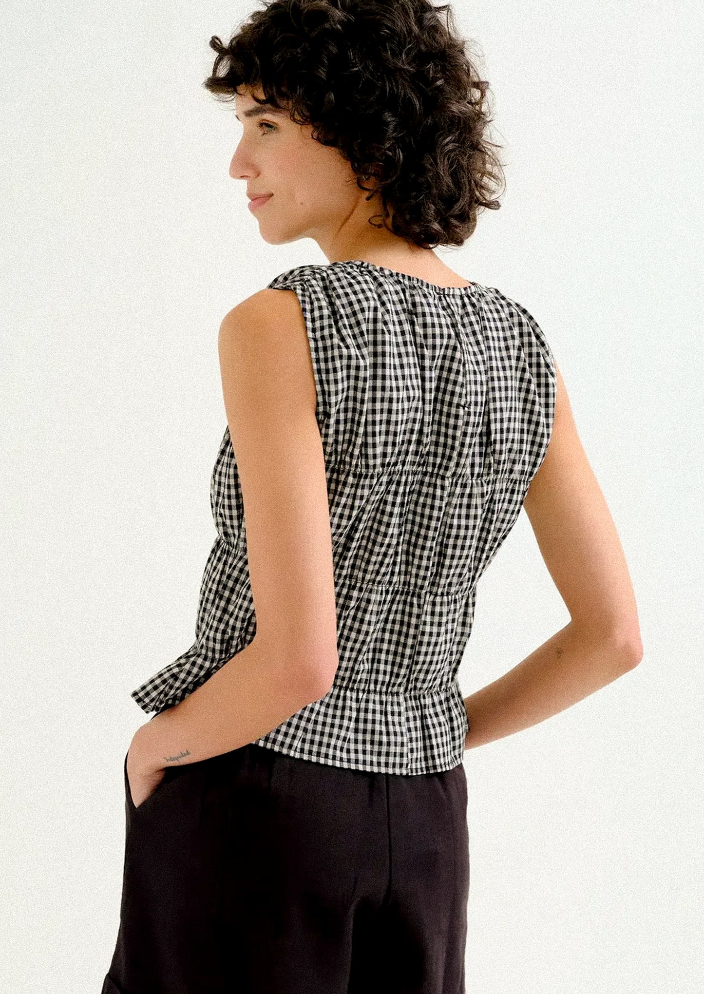 A woman wearing a black and white gingham sleeveless top.