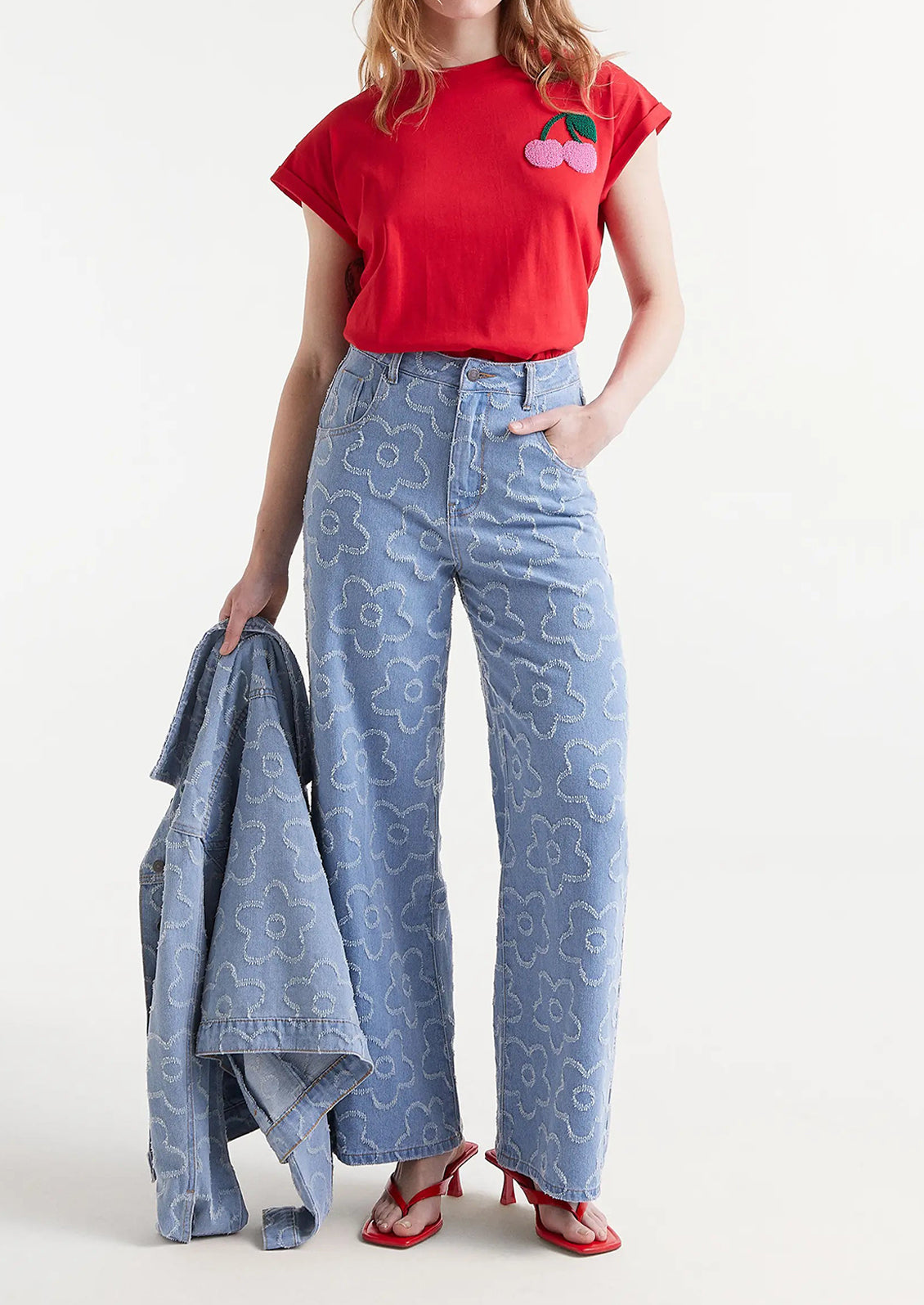 A woman wearing a pair of denim jeans with jacquard flower pattern throughout.