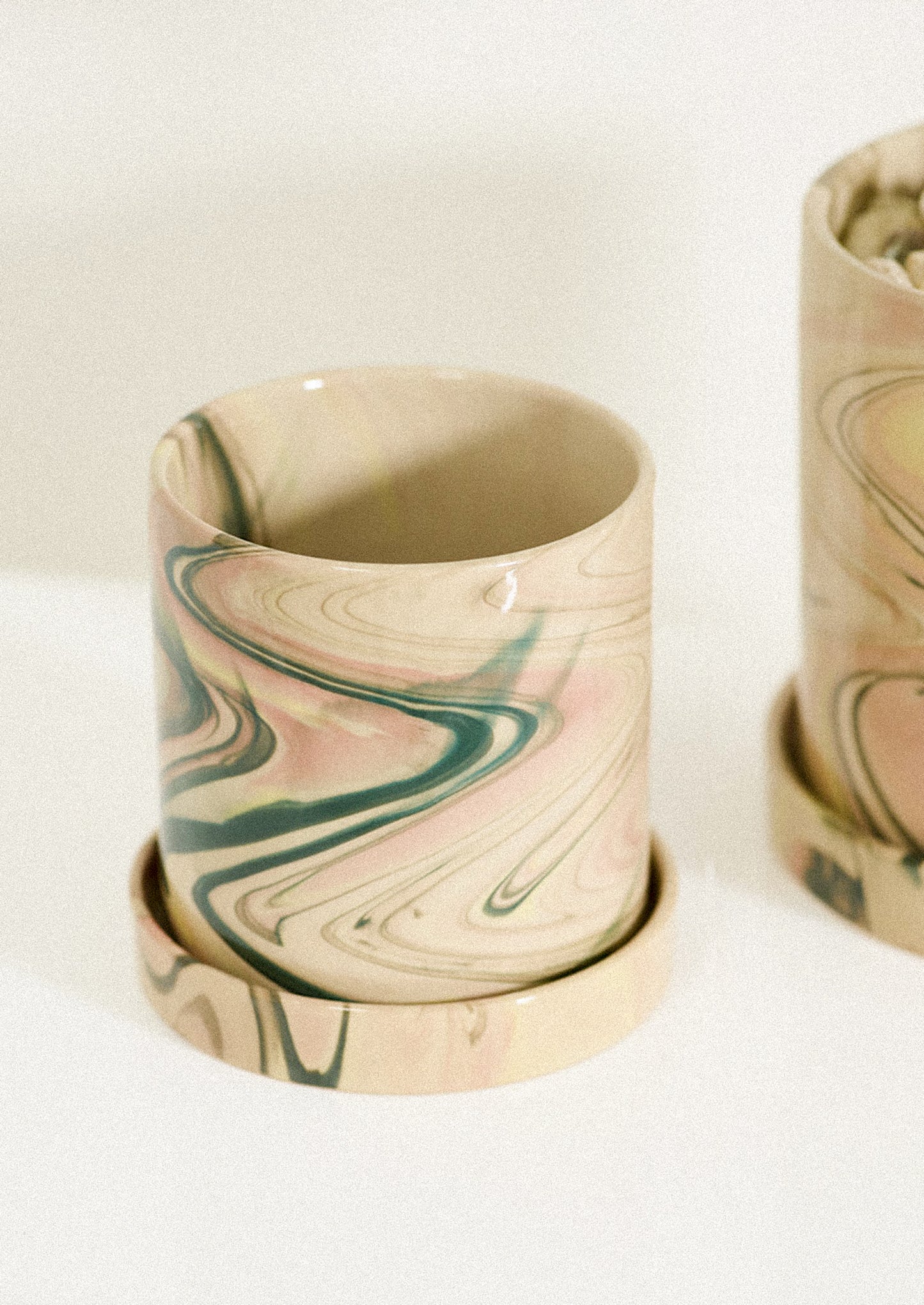 A ceramic planter in tan with pastel marbleized pattern.