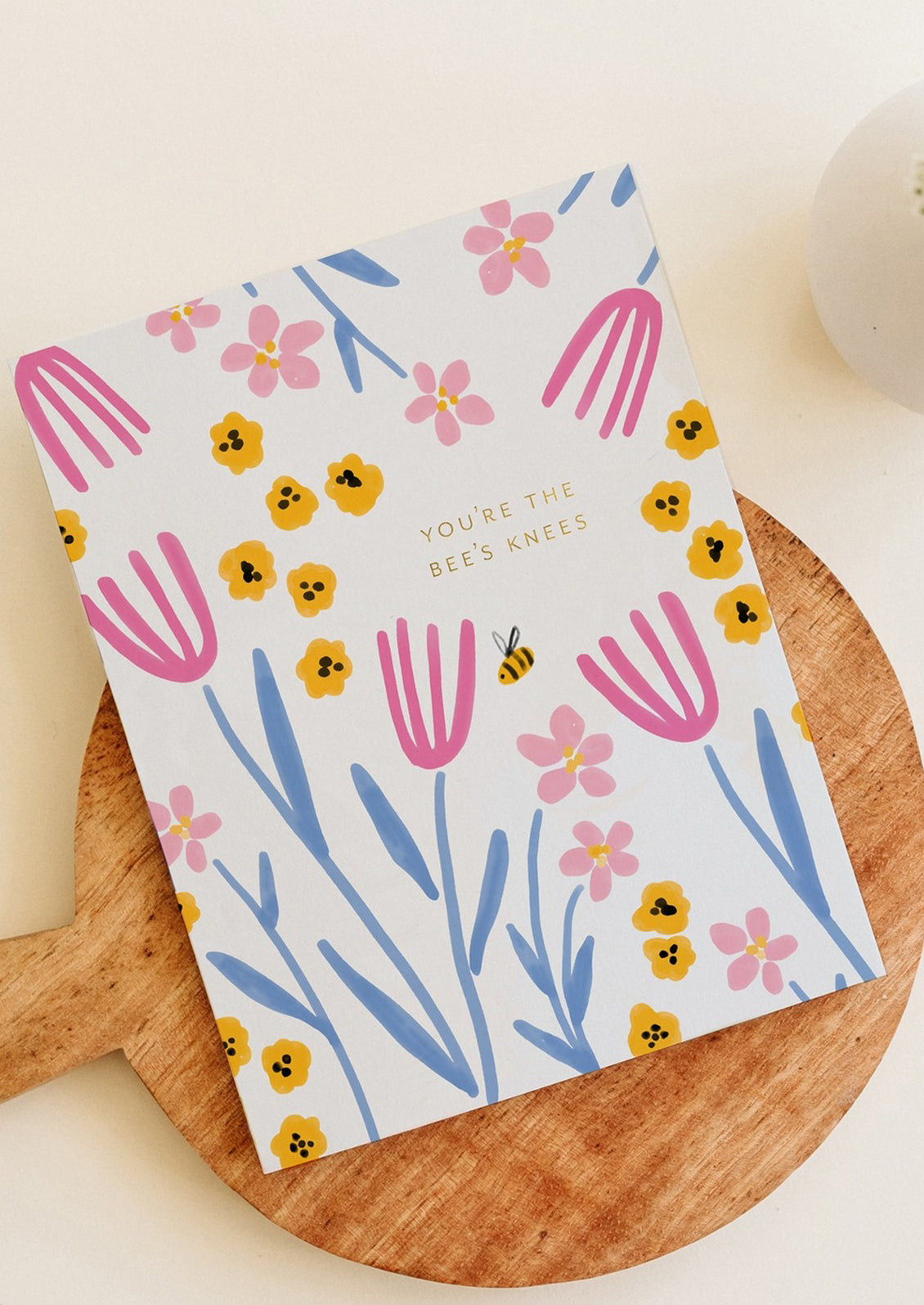 A floral print greeting card with gold text reading "You're The Bees Knees".