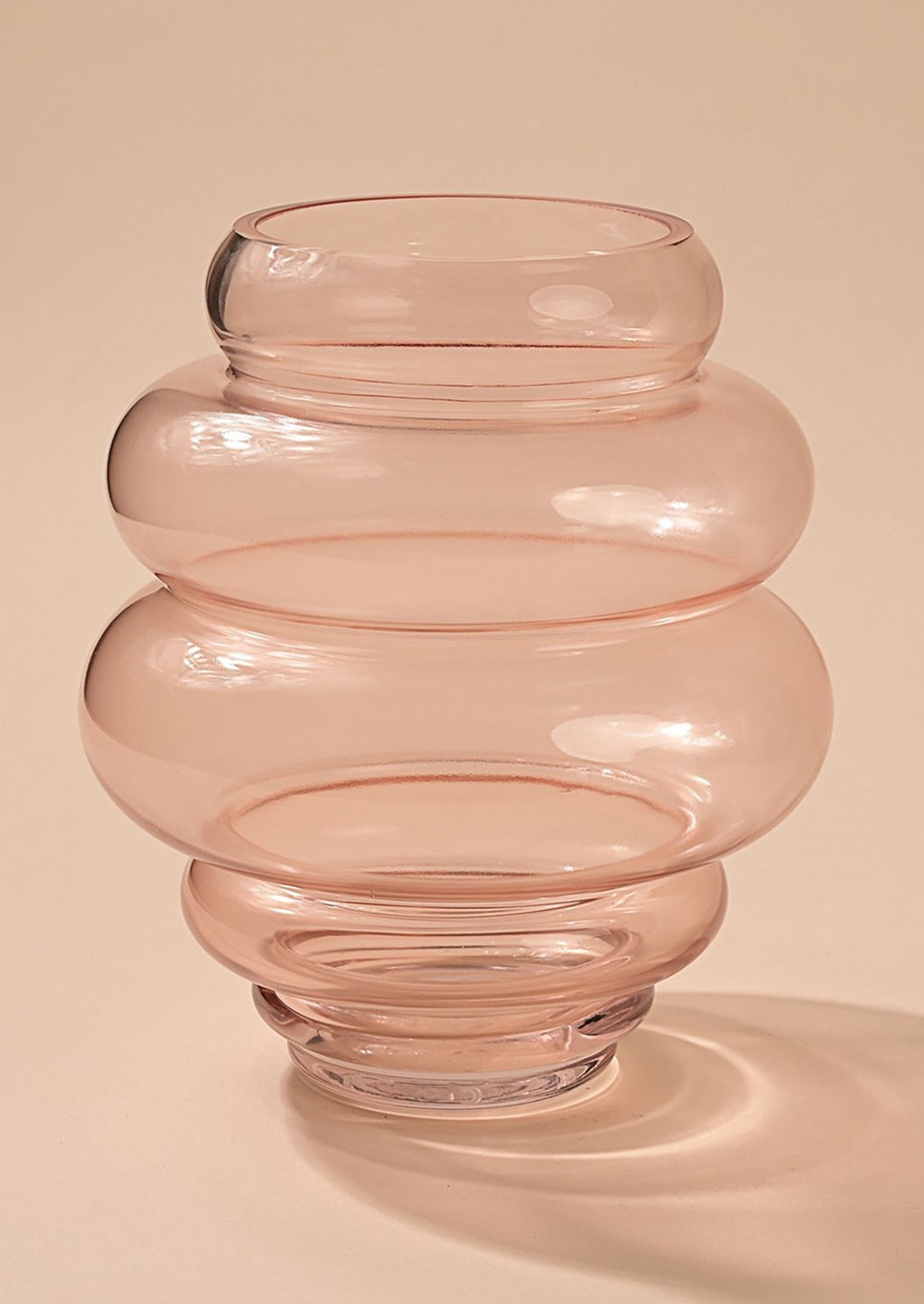 A glass vase in translucent pink glass with bulbous curvy shape.