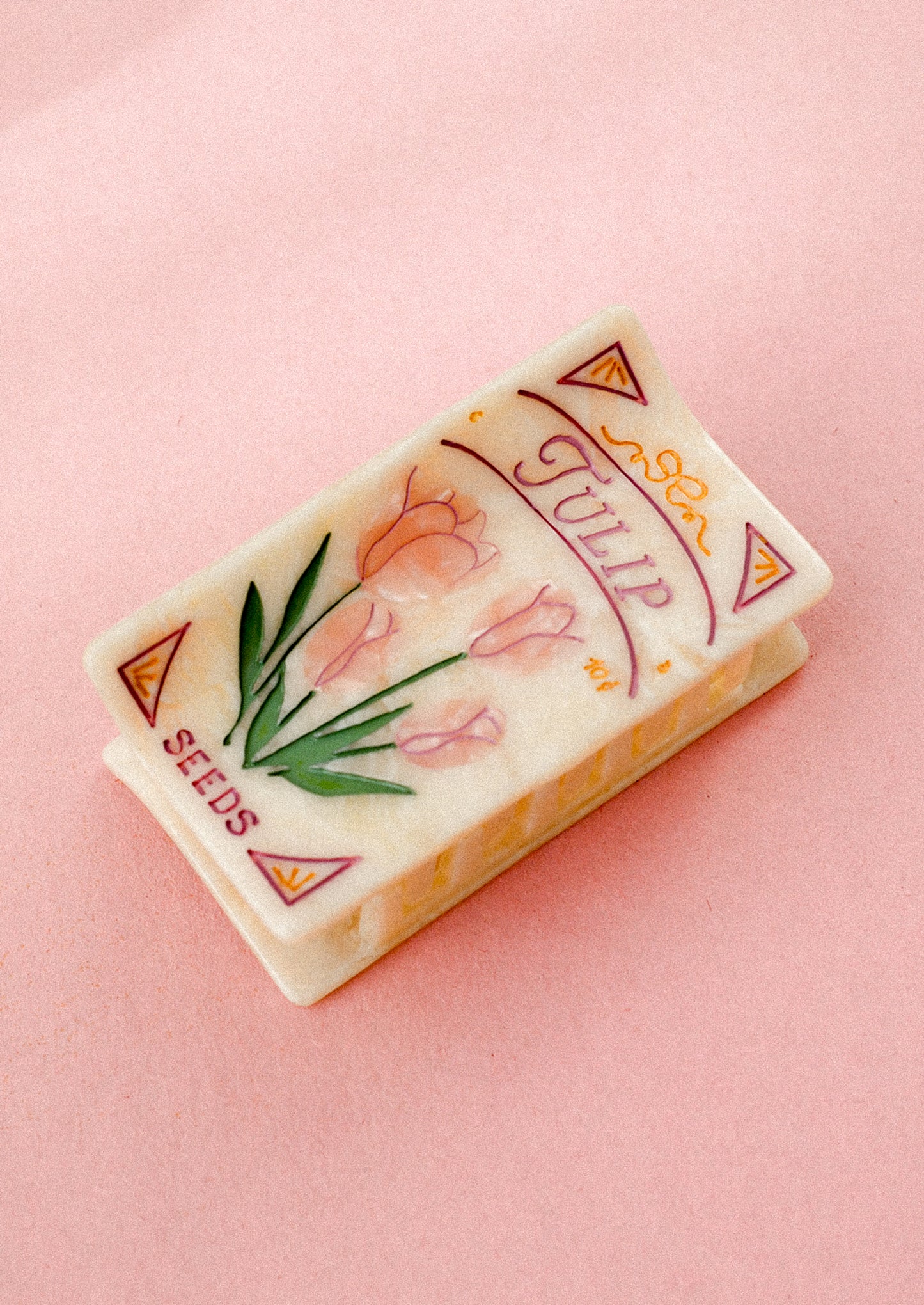 Vintage-style tulip seed packet style hair clip on a pink background