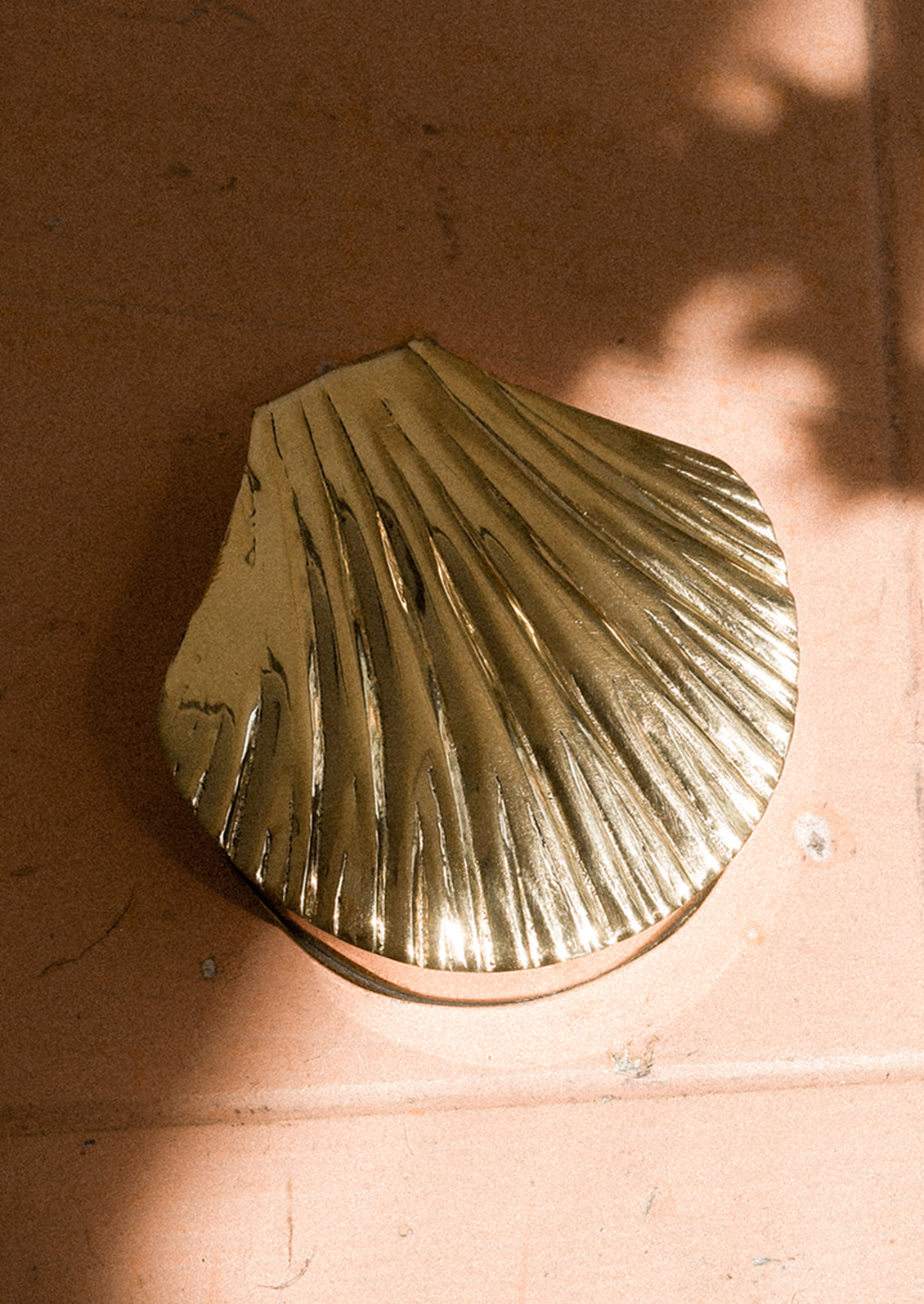 A gold shell-shaped trinket box on a wooden surface.