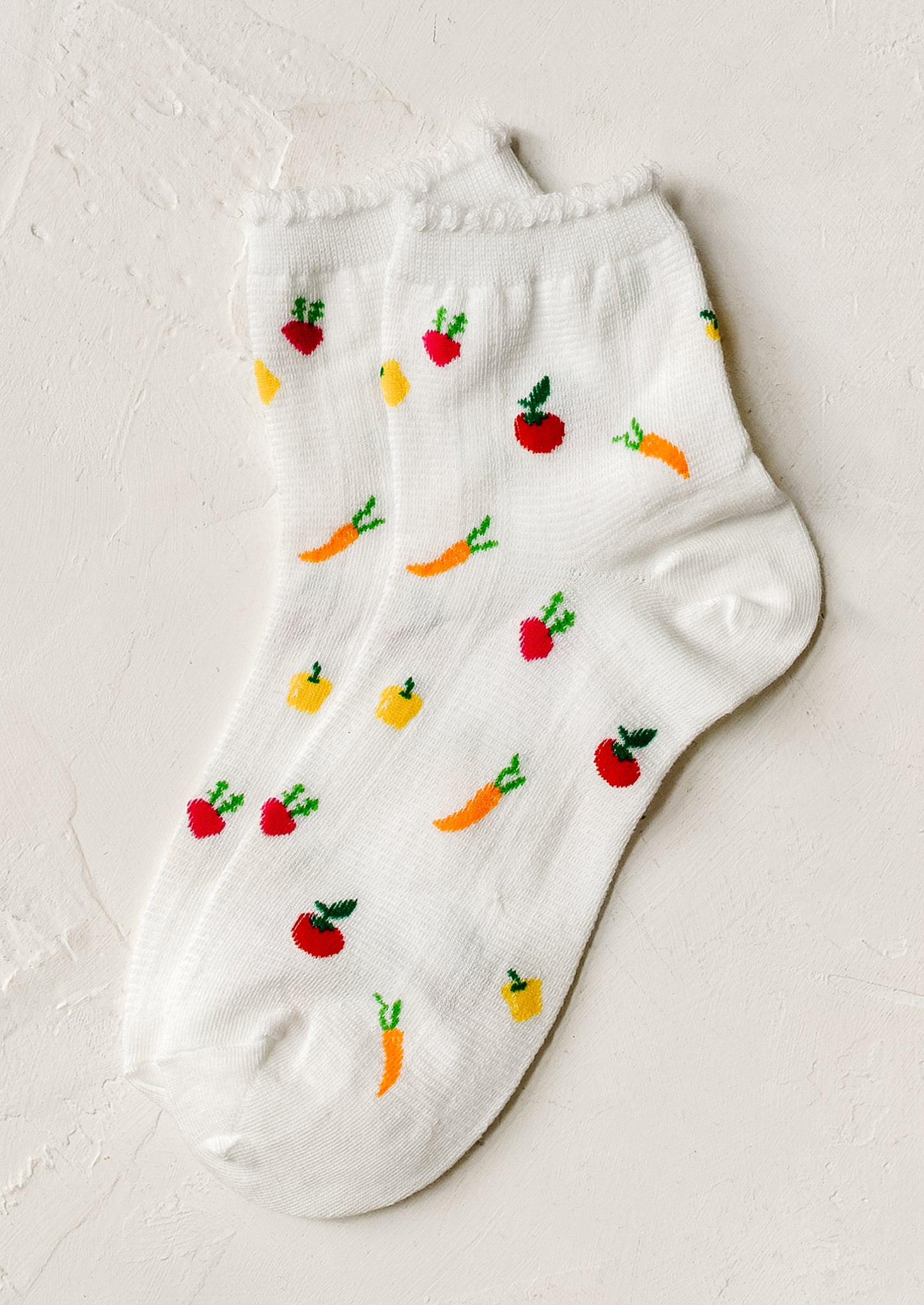 A pair of white socks with all over vegetable motif.