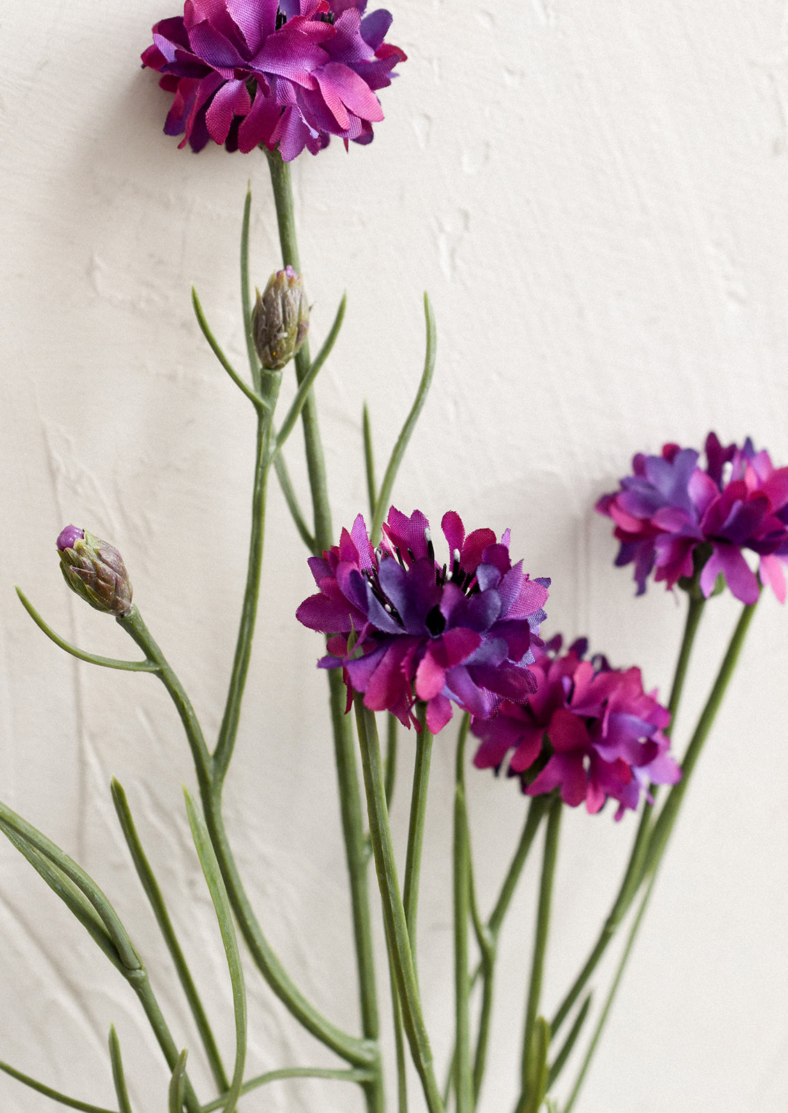 A faux floral spray depicting mini cornflower in purple.