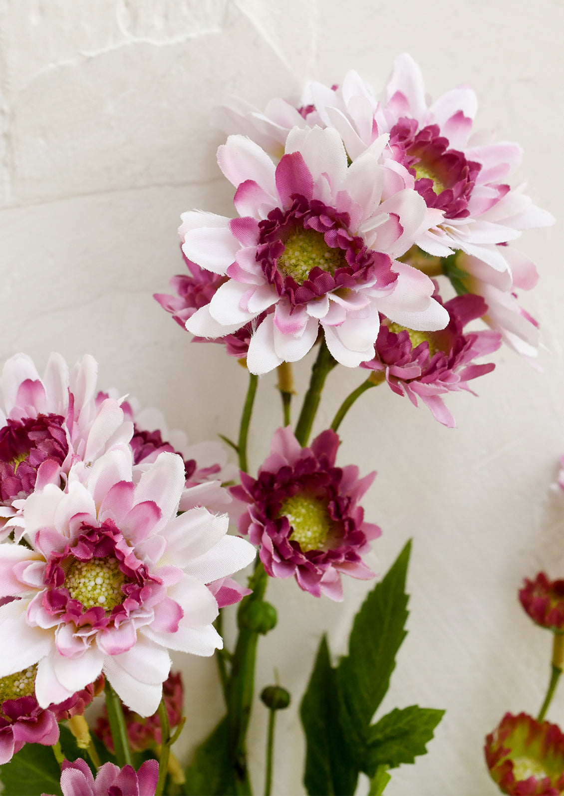 Artificial flower branch with pink and purple flowers on a white background