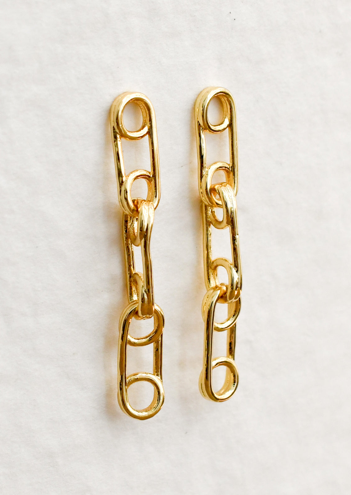A pair of gold drop earrings with triple linked pin design.