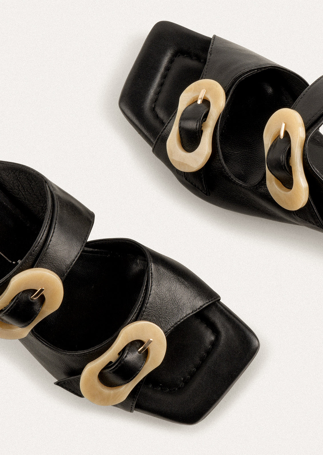 A square toe heeled sandal in black with double tan buckle detail.