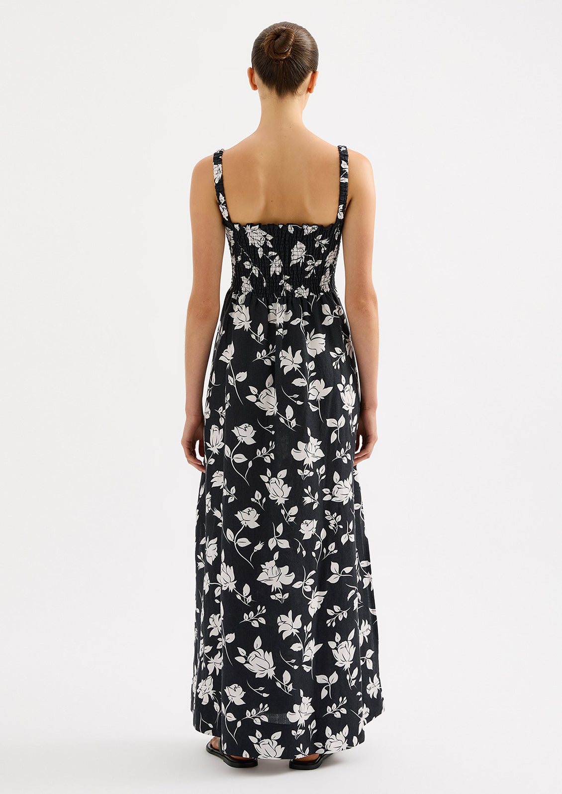 A woman wearing a black and white floral print maxi dress with smocked bodice.