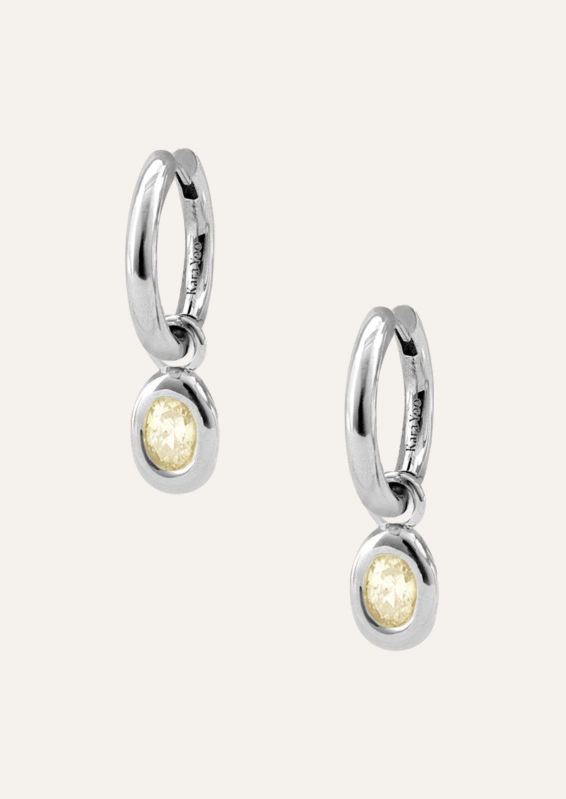 A pair of sterling silver hoop earrings with a pale yellow gem.