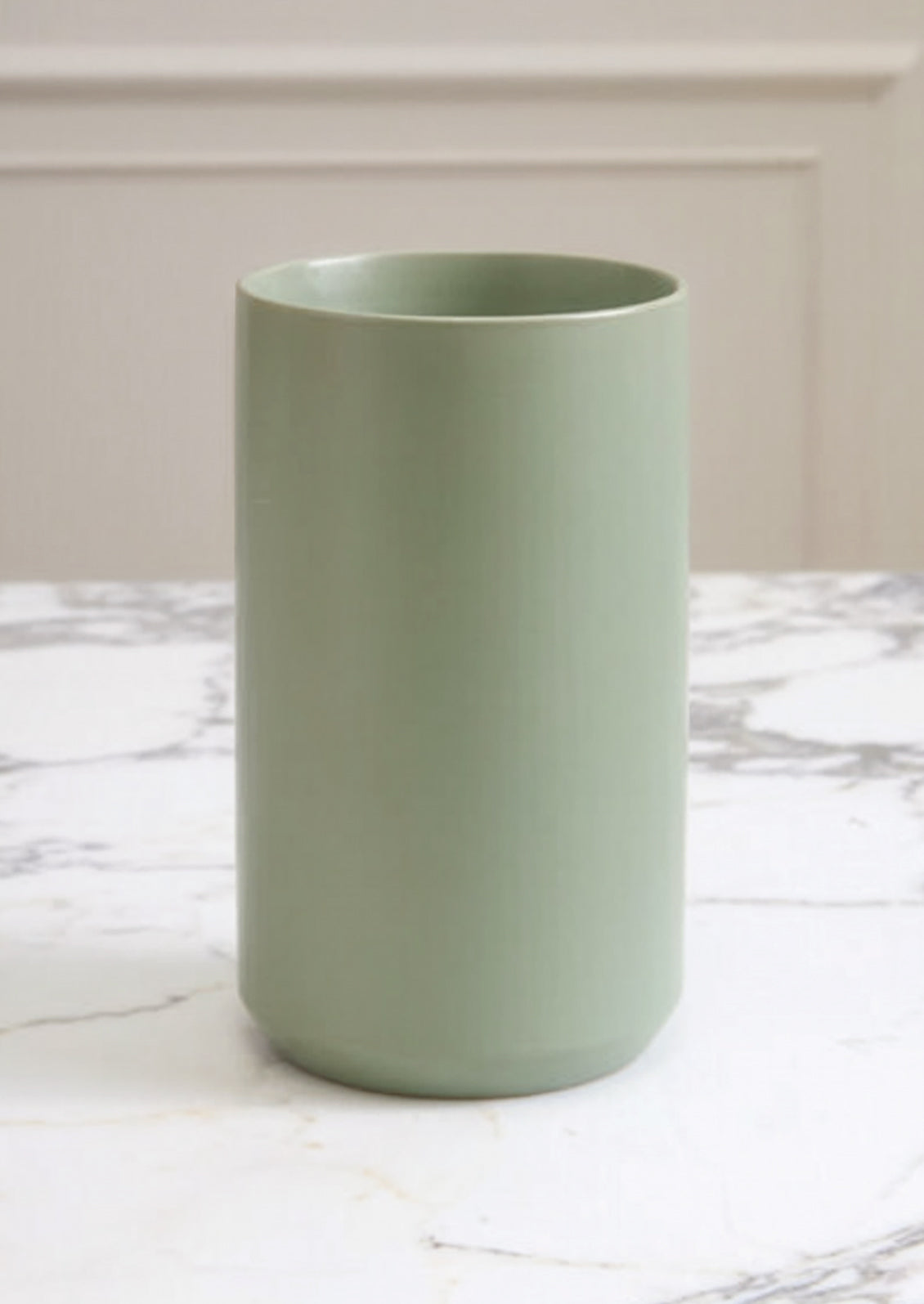 Aquamarine cylindrical vase on a marble surface with a neutral background