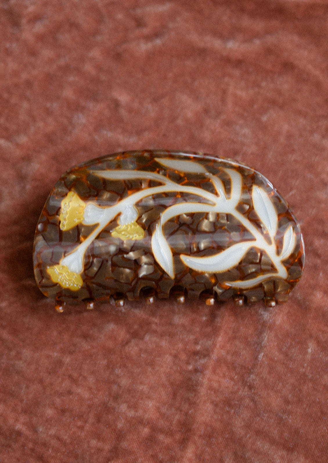 A brown tortoiseshell hair claw with yellow flower.