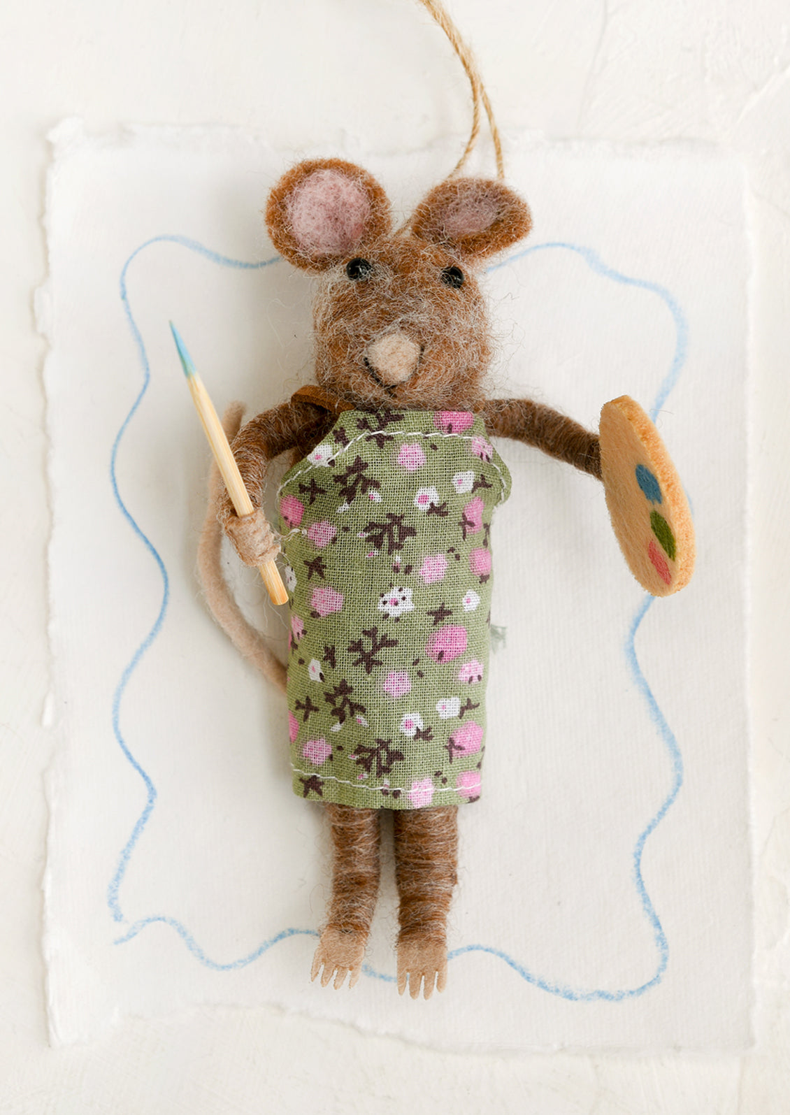 A felted mouse ornament wearing apron and holding paintbrush and palette.