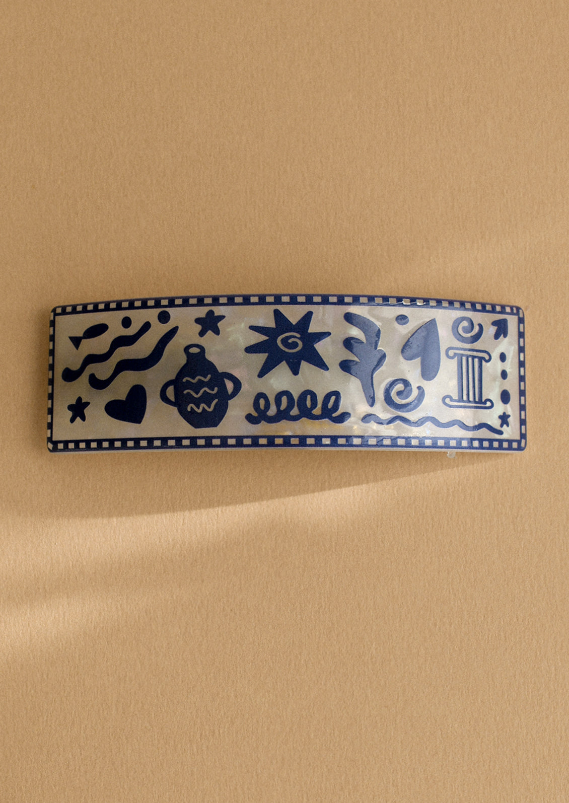 A pearl white barrette with grecian inspired vacation print.