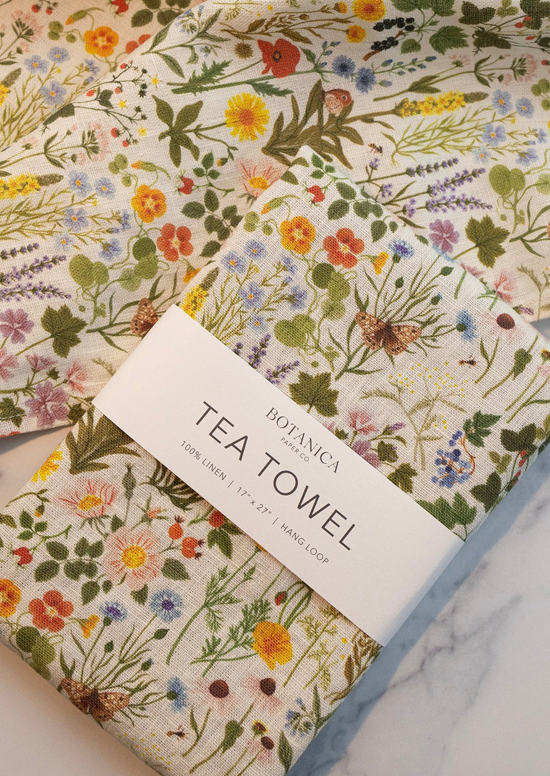 A linen tea towel with multicolor floral/botanical print.