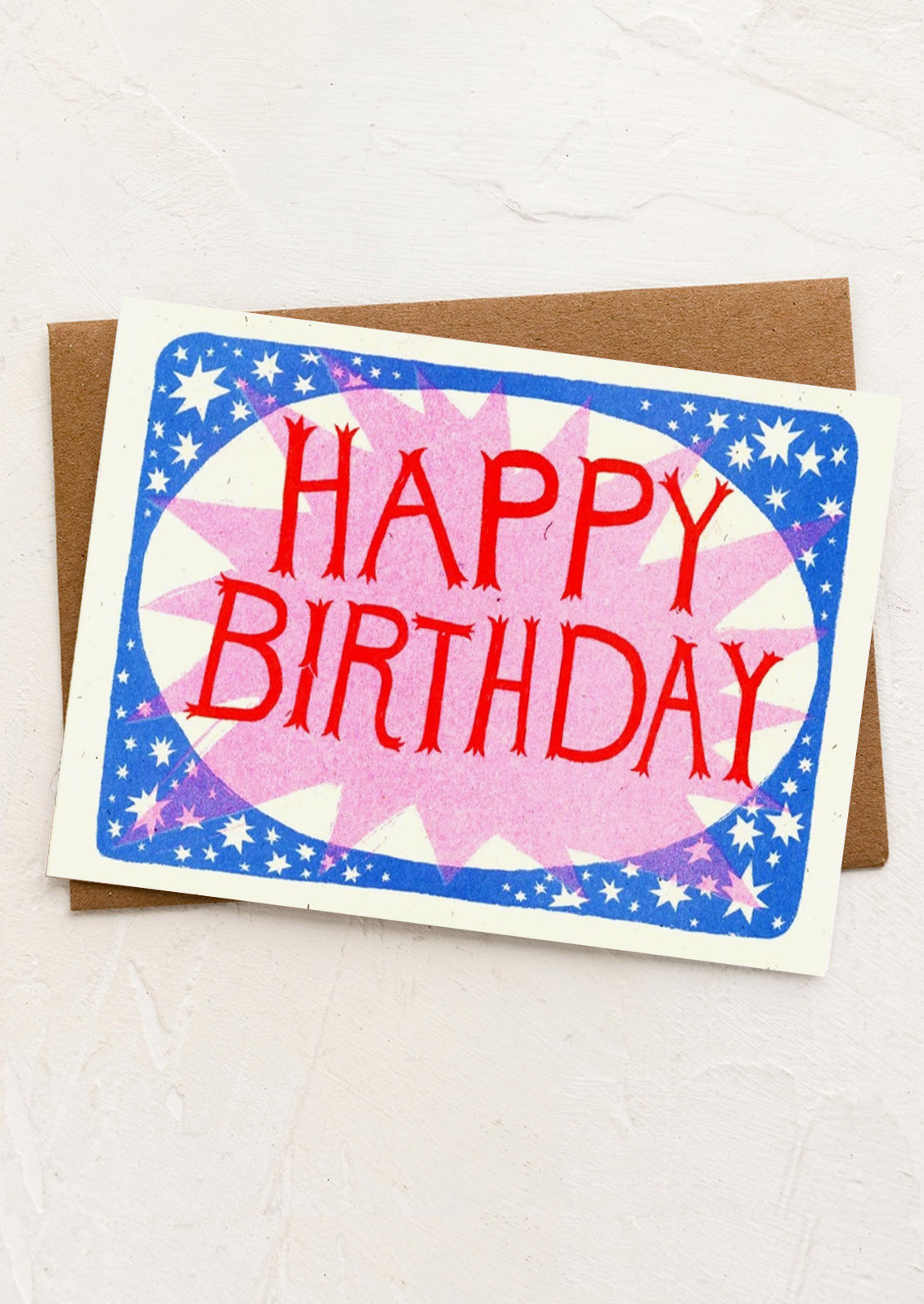 A greeting card with pink starburst and red birthday lettering.
