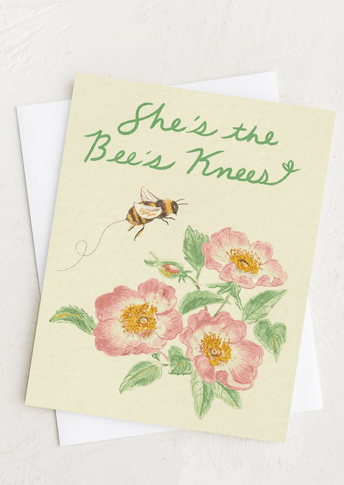 A greeting card with floral print reading "She's the bee's knees".