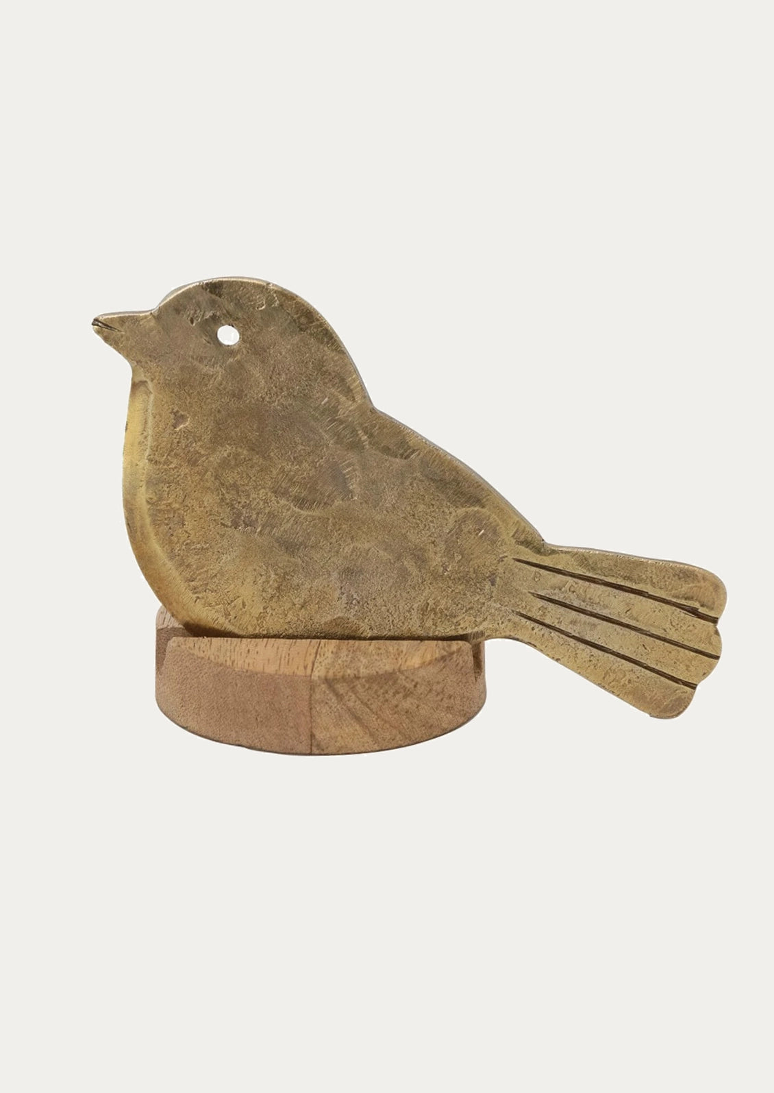 A brass cheese knife shaped like a bird, resting on wooden stand.