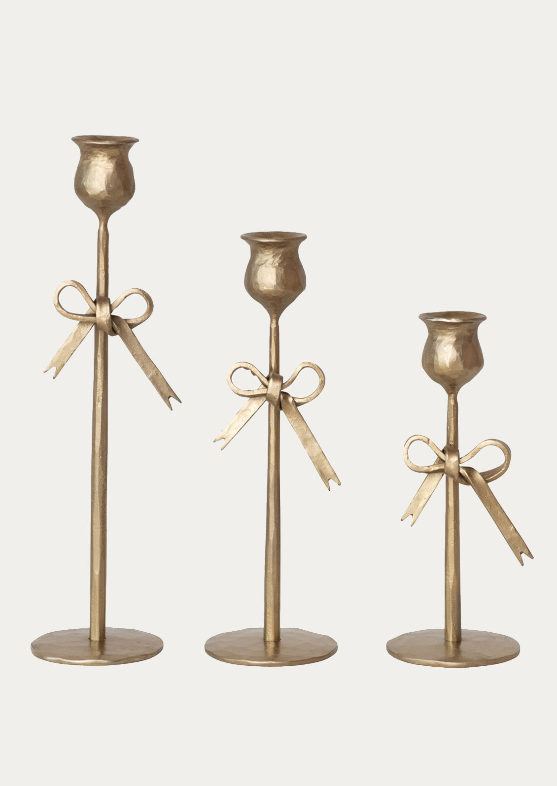 Three gold candle holders with ribbons on a white background