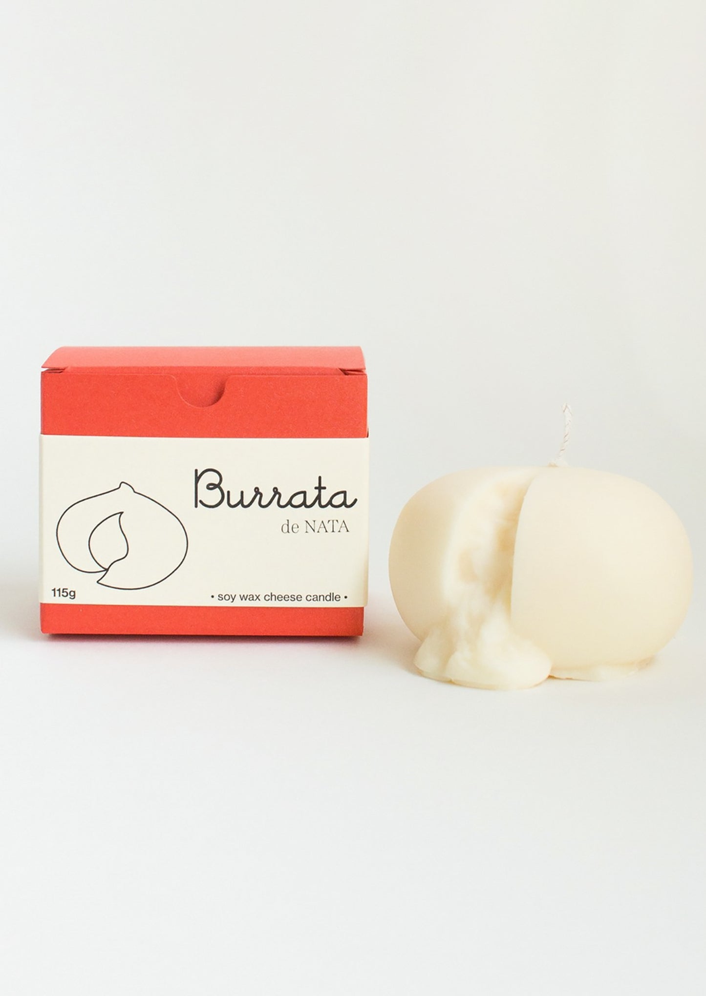 A candle in the shape of a ball of burrata cheese, with red gift box.