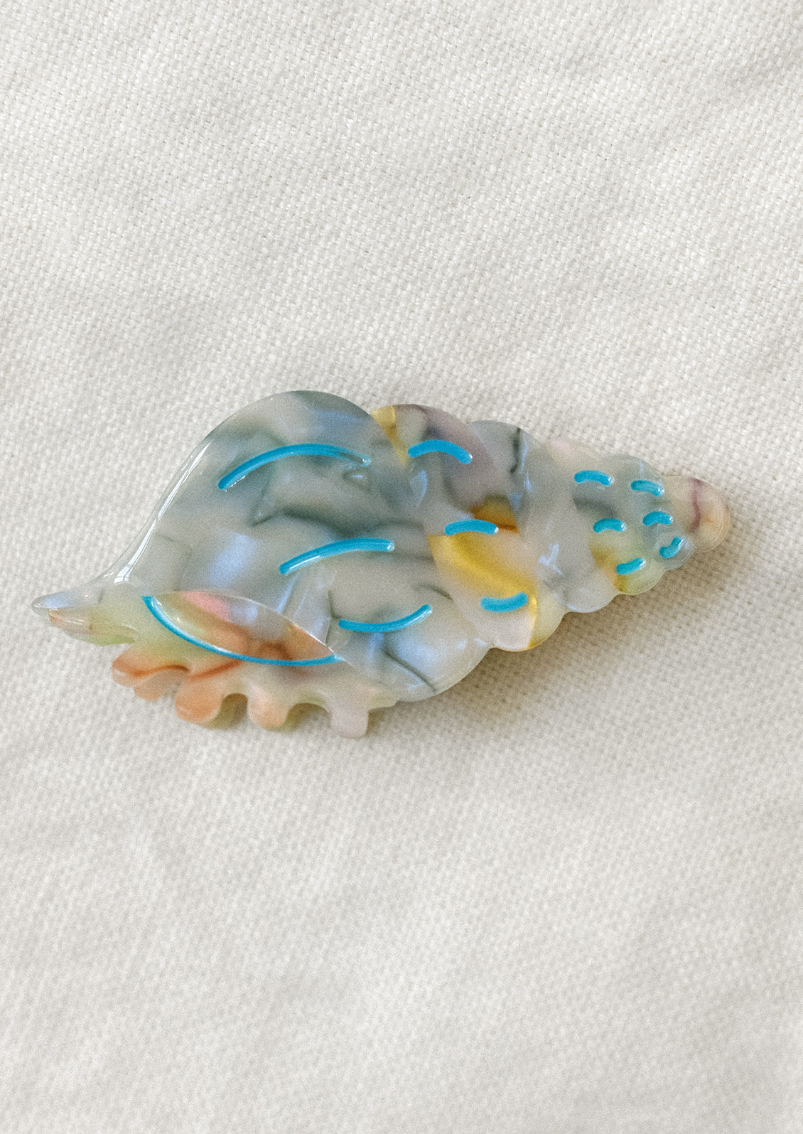 A hair claw in shape of conch shell, multicolor.
