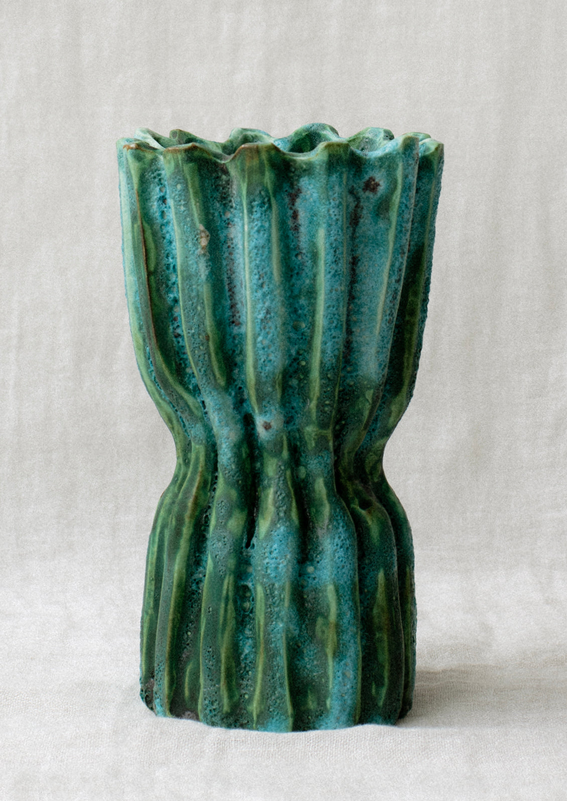 A ridge textured, turquoise hue ceramic vase.