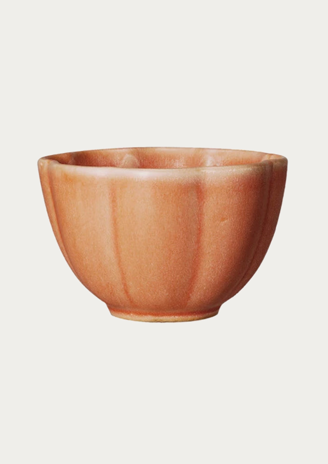 A ceramic snack bowl with scalloped shape in peach.