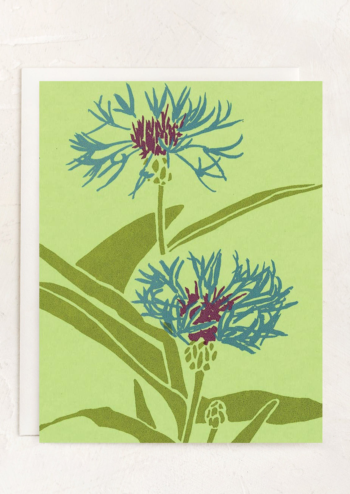 A green greeting card with illustration of bachelor's button flower.