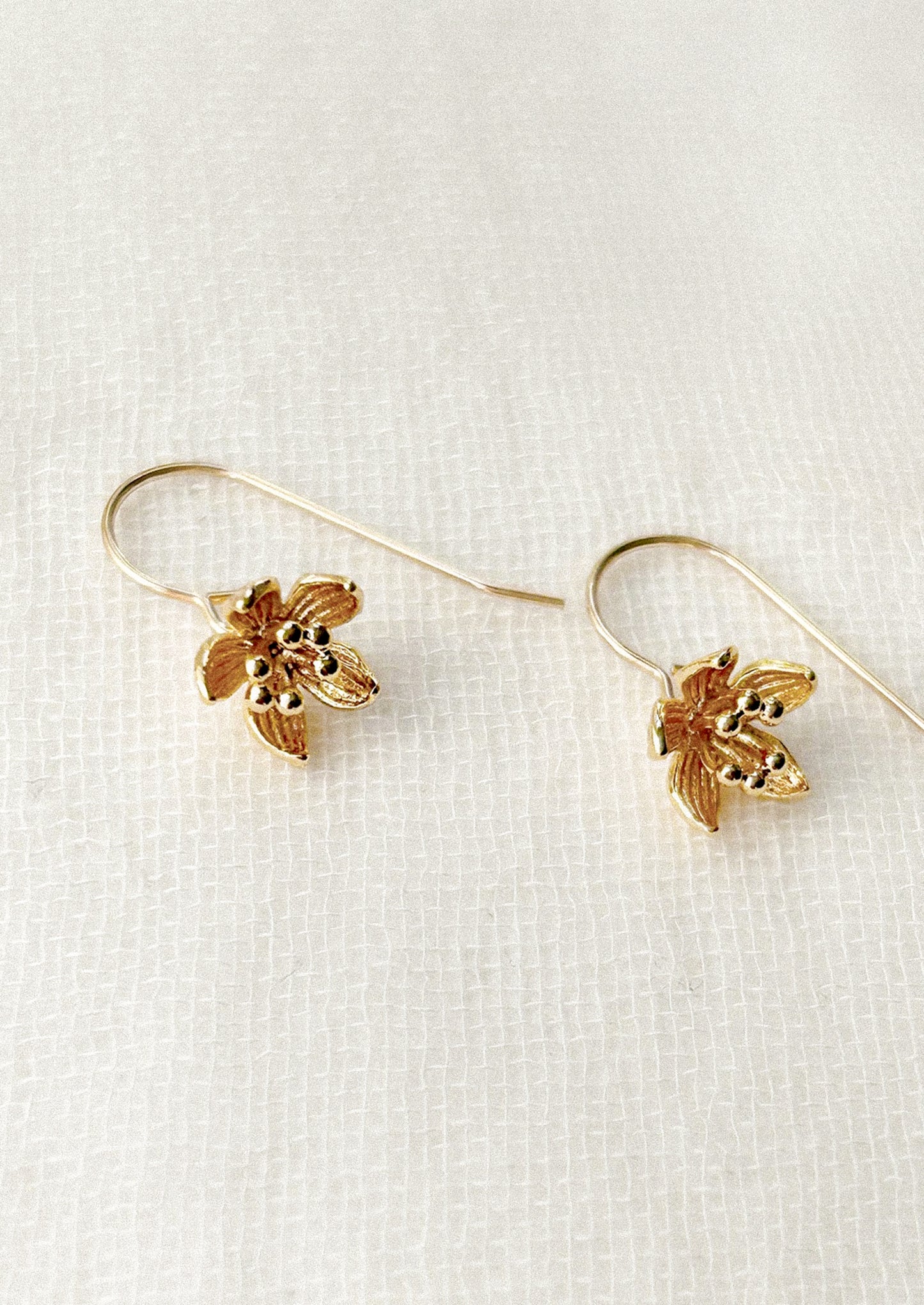 Gold flower-shaped earrings on a white background