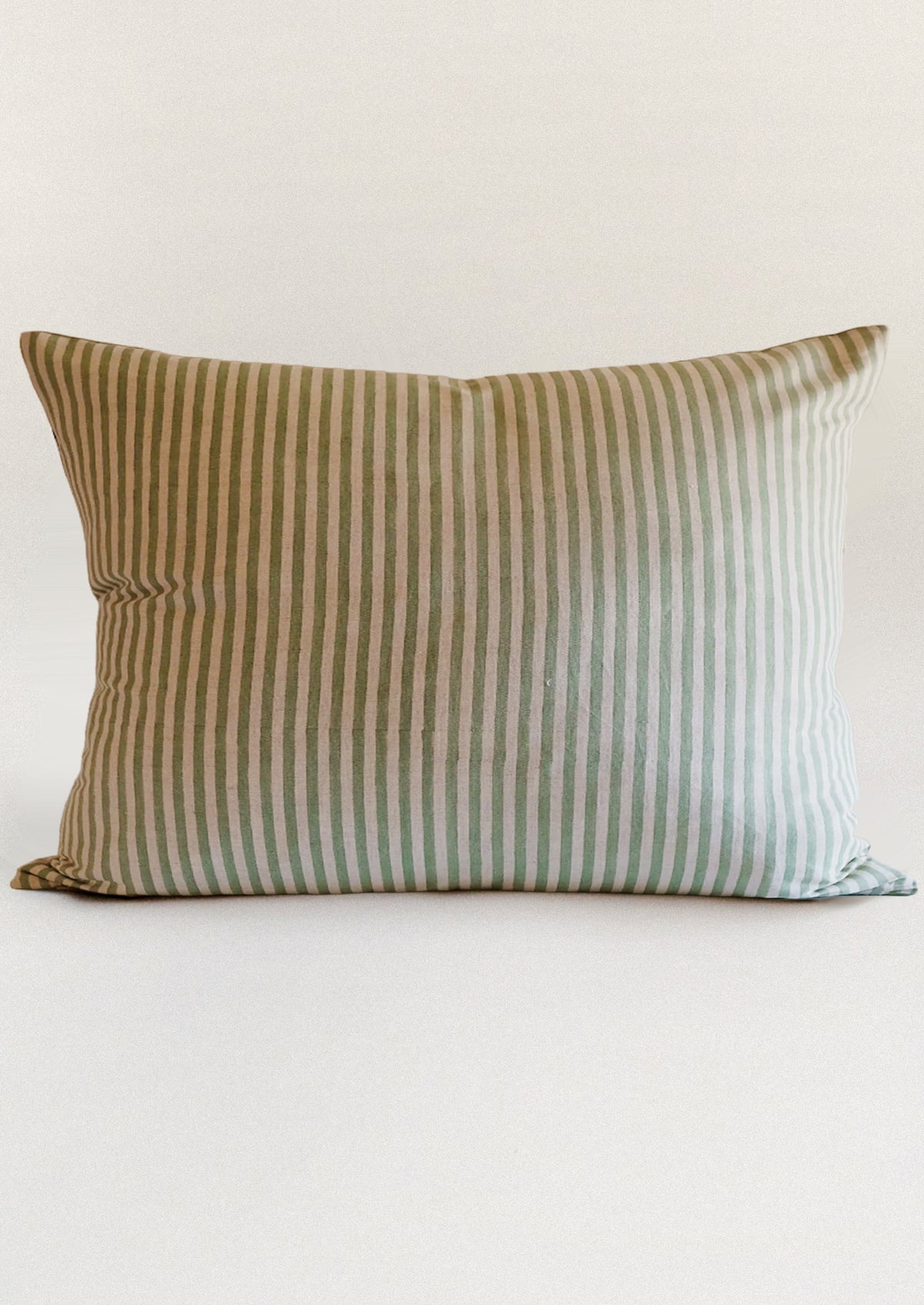 A block printed throw pillow in green stripe pattern.