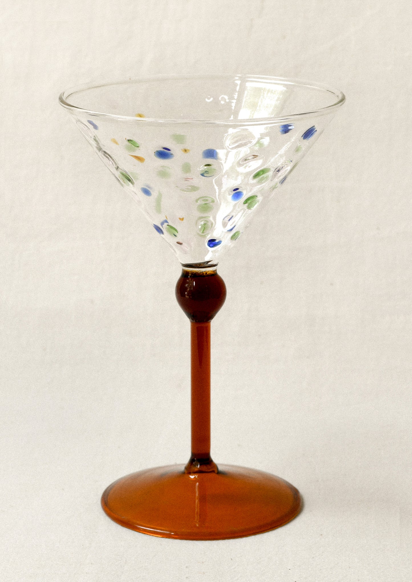 Decorative martini glass with colorful dots and amber stem.