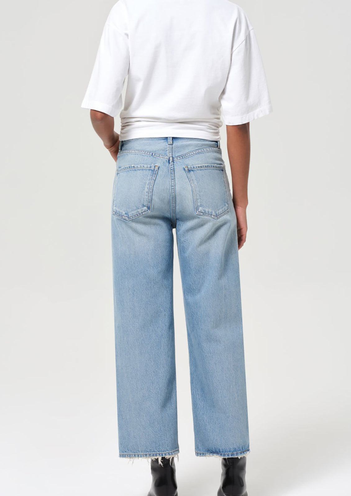 Person wearing light blue jeans and a white shirt on a plain background