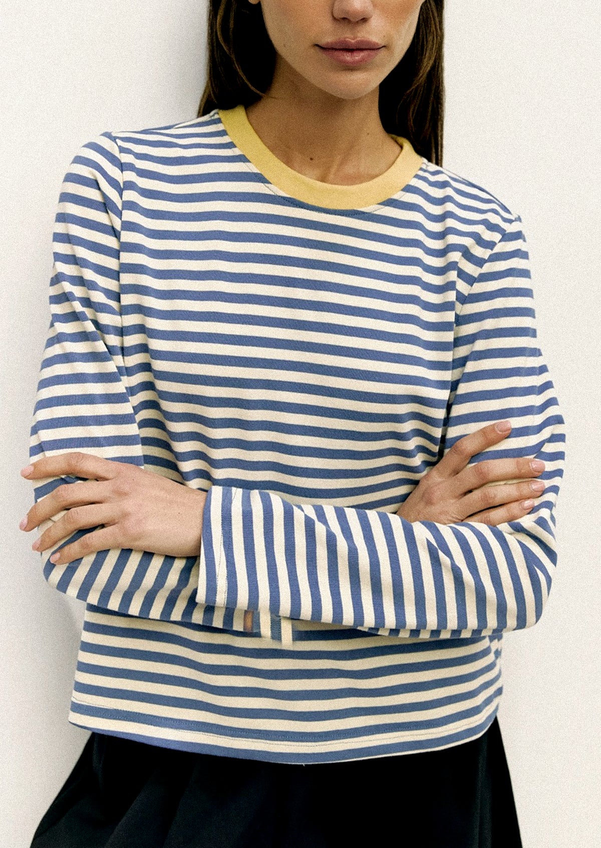 Person wearing a blue and white striped shirt with a yellow collar against a white background