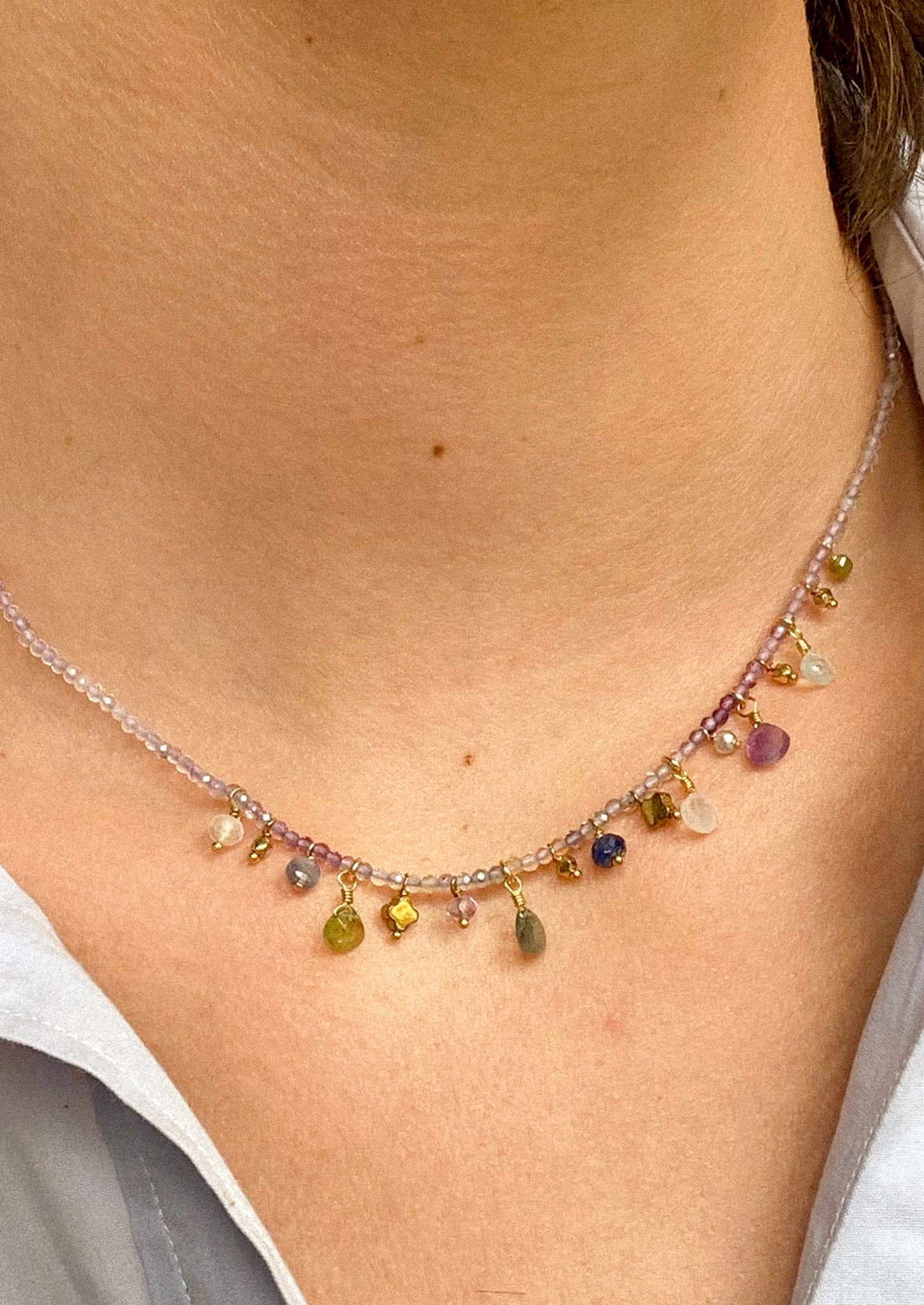 A purple gemstone beaded necklace with assorted gemstone charms.