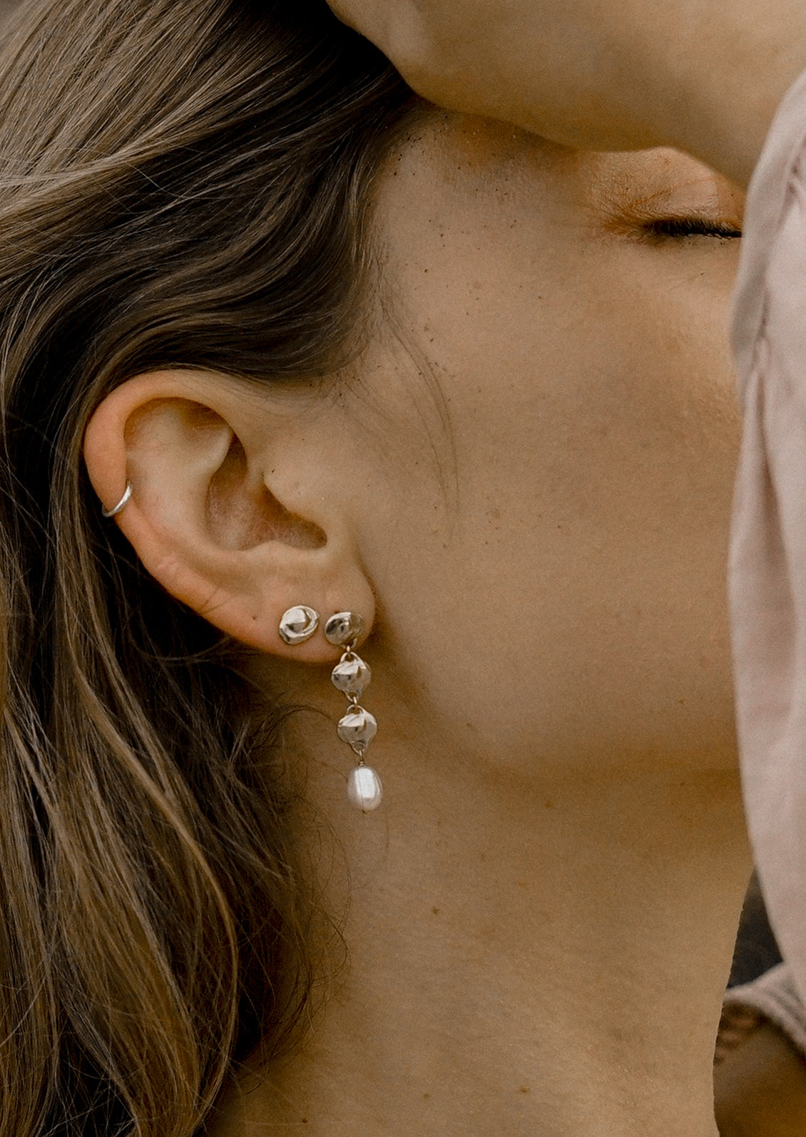 A pair of sterling silver earrings with triple pendant style and pearl charm.