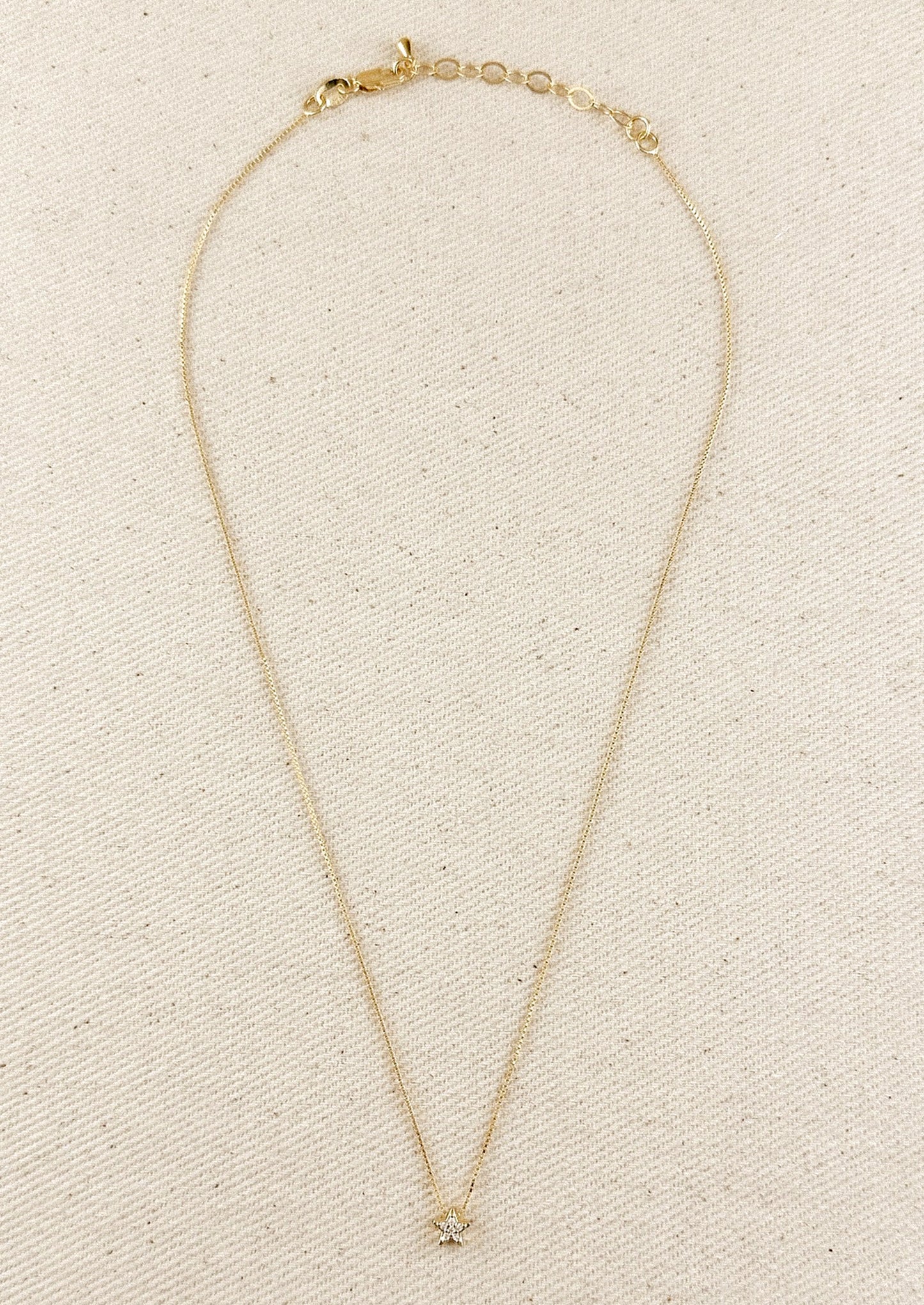 A gold box chain necklace with small gold & crystal star charm.