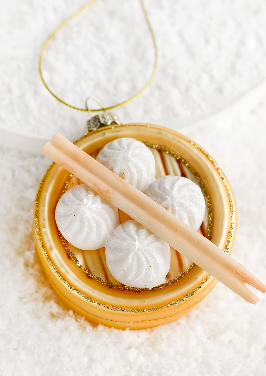 A glass ornament of tray of steamed buns with chopsticks.