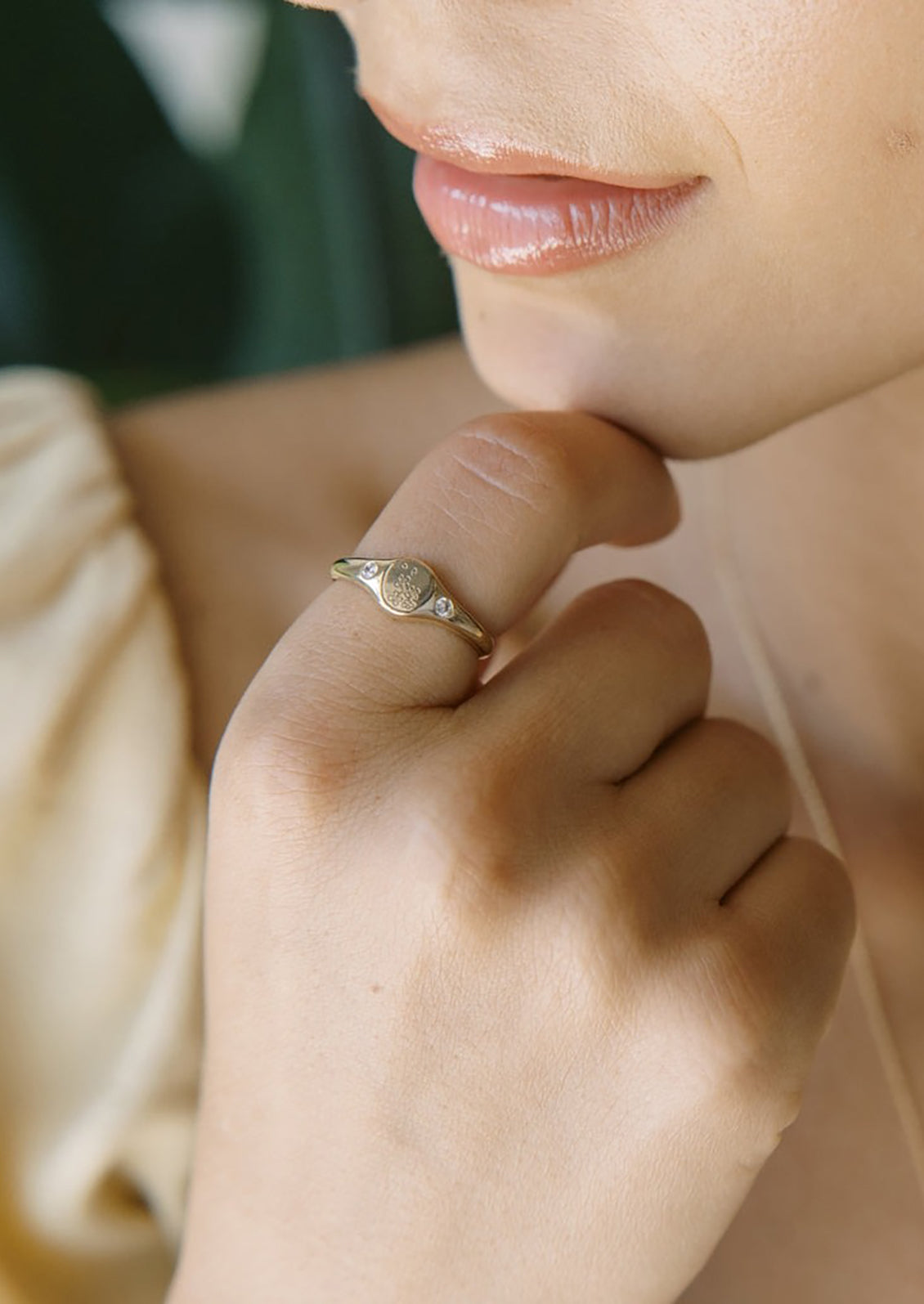 A gold signet ring with floral engraving with clear crystal on either side.
