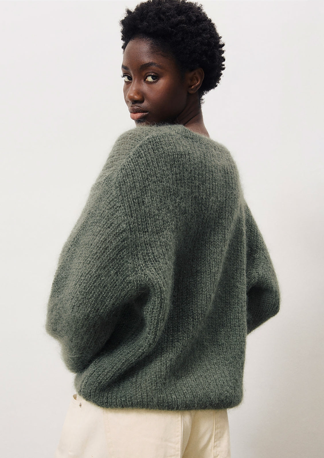 A woman wearing a mohair sweater in dusty khaki grey-green color.