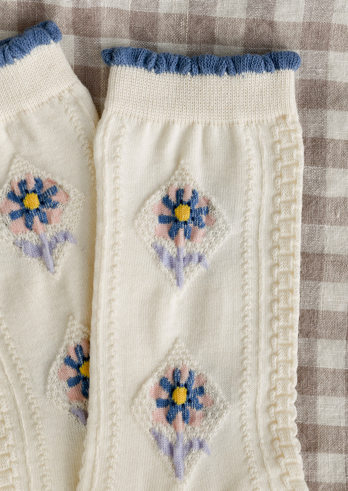 A pair of cream socks with pink, yellow, blue and lavender floral pattern.