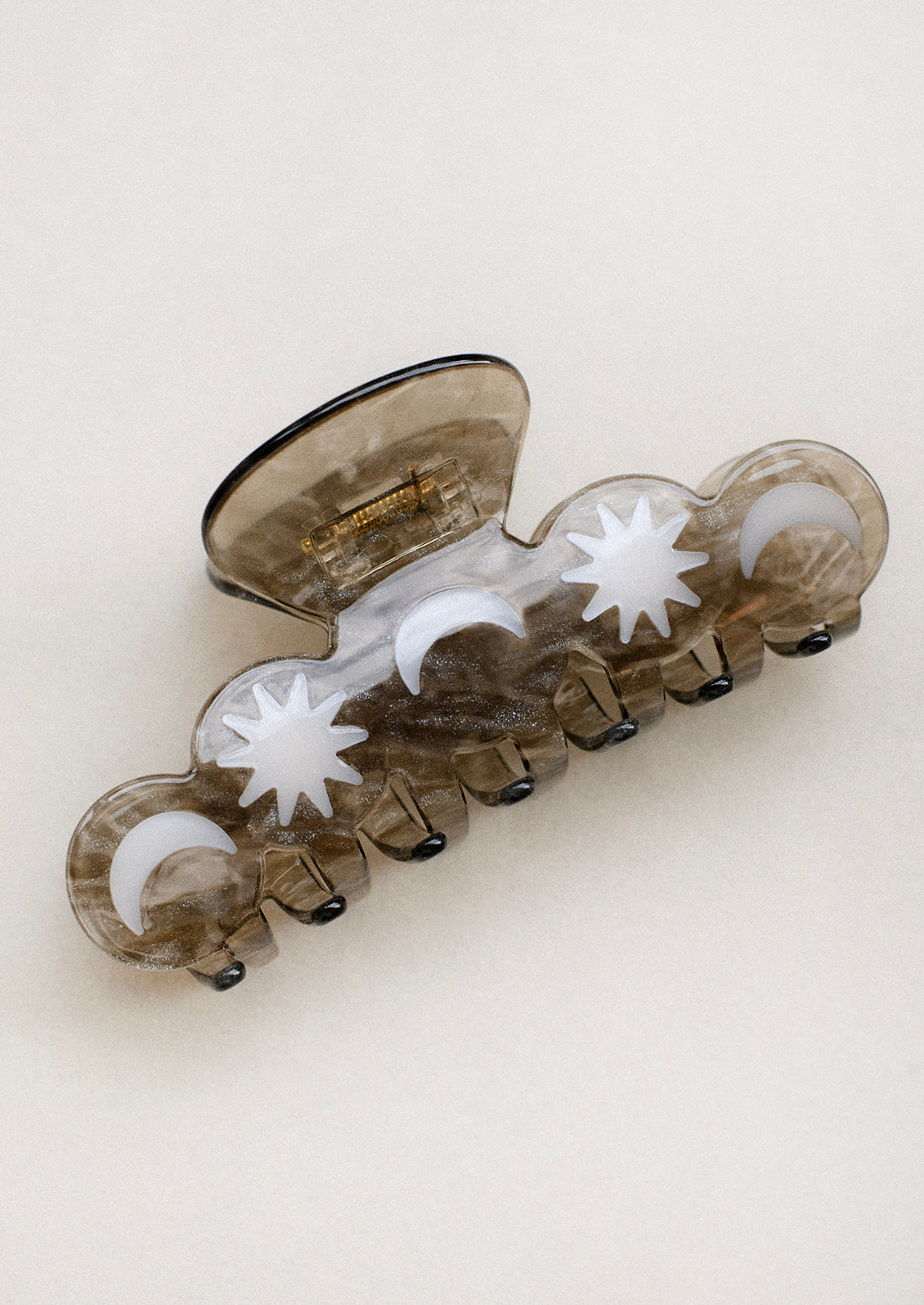 A pewter color hair claw with moon and star pattern.
