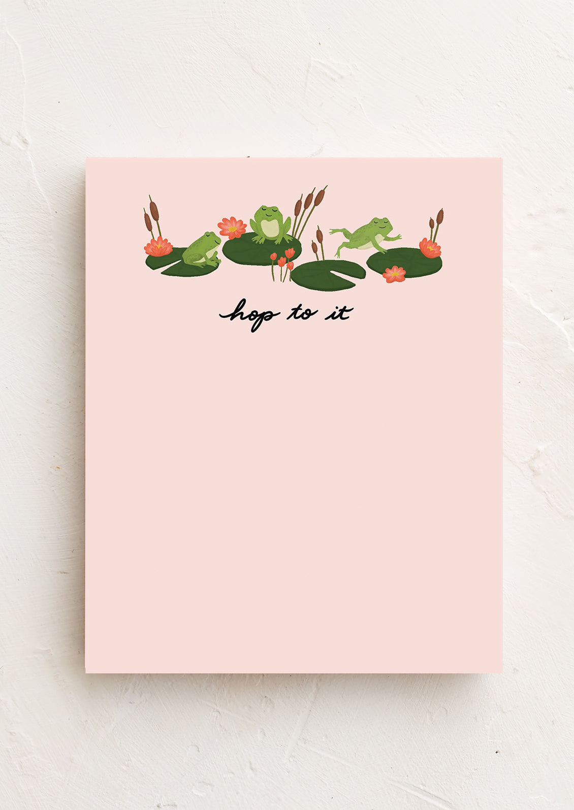 A pink notepad with a floral pattern and the phrase 'hop to it' written at the bottom