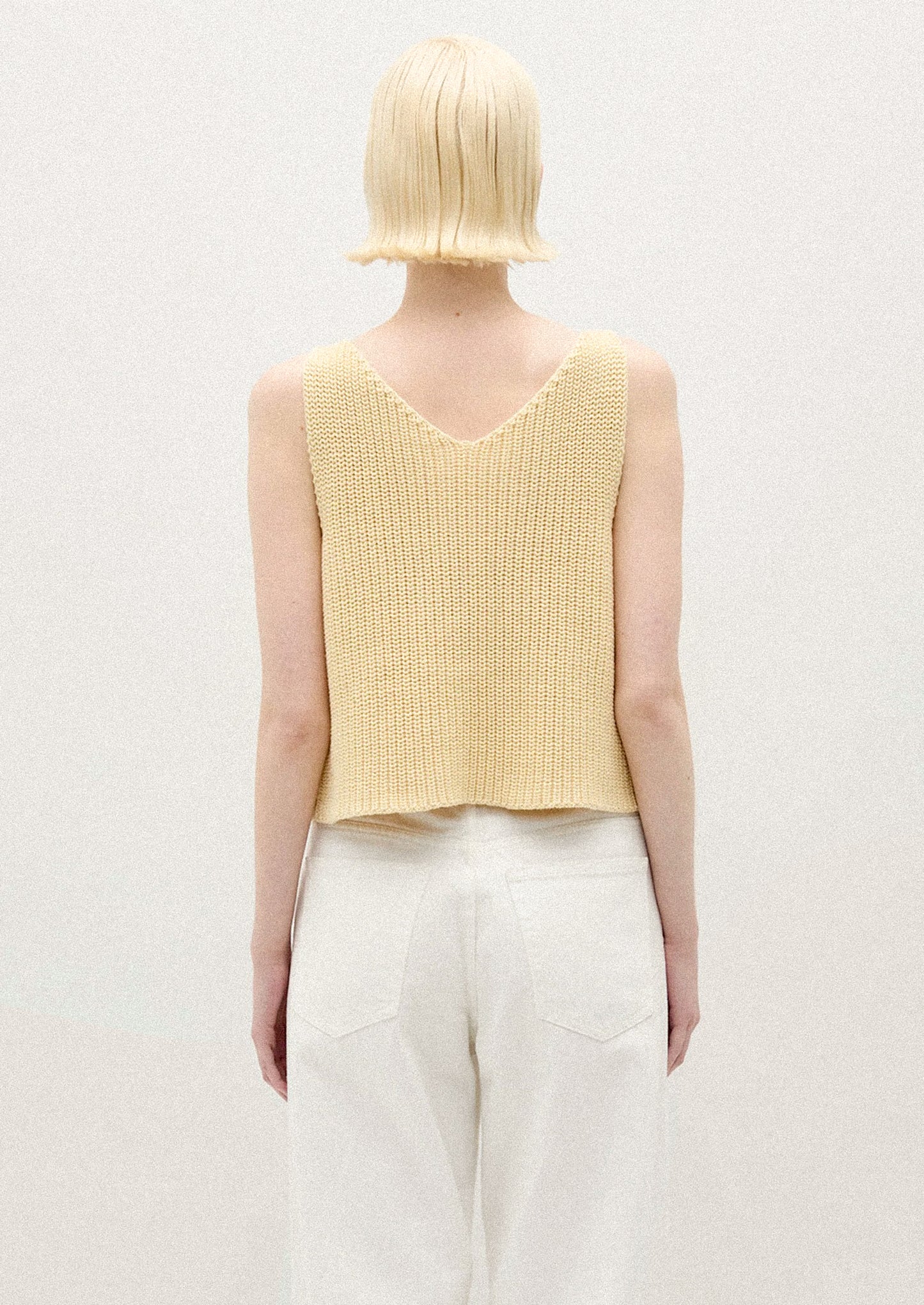 A person wearing a sleeveless knit vest in two tone yellow.
