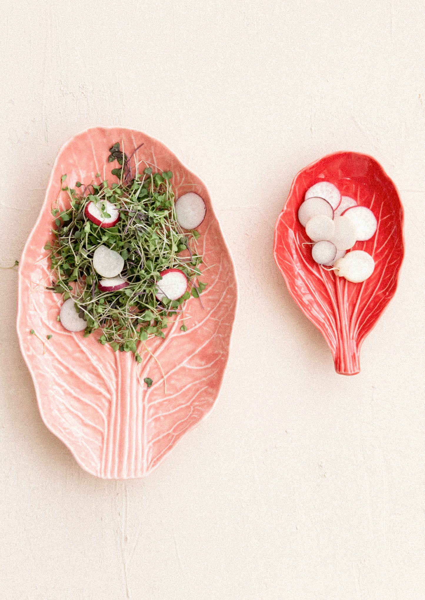 Two ceramic leaf-shaped plates with decorative items on a light background