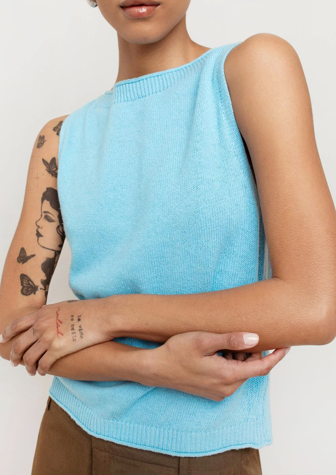 A person wearing a knit top with high neckline in bright cyan color.