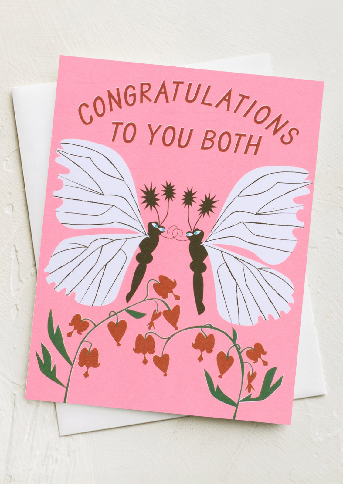 A neon pink card with illustration of two moths kissing, text reads "Congratulations to you both".