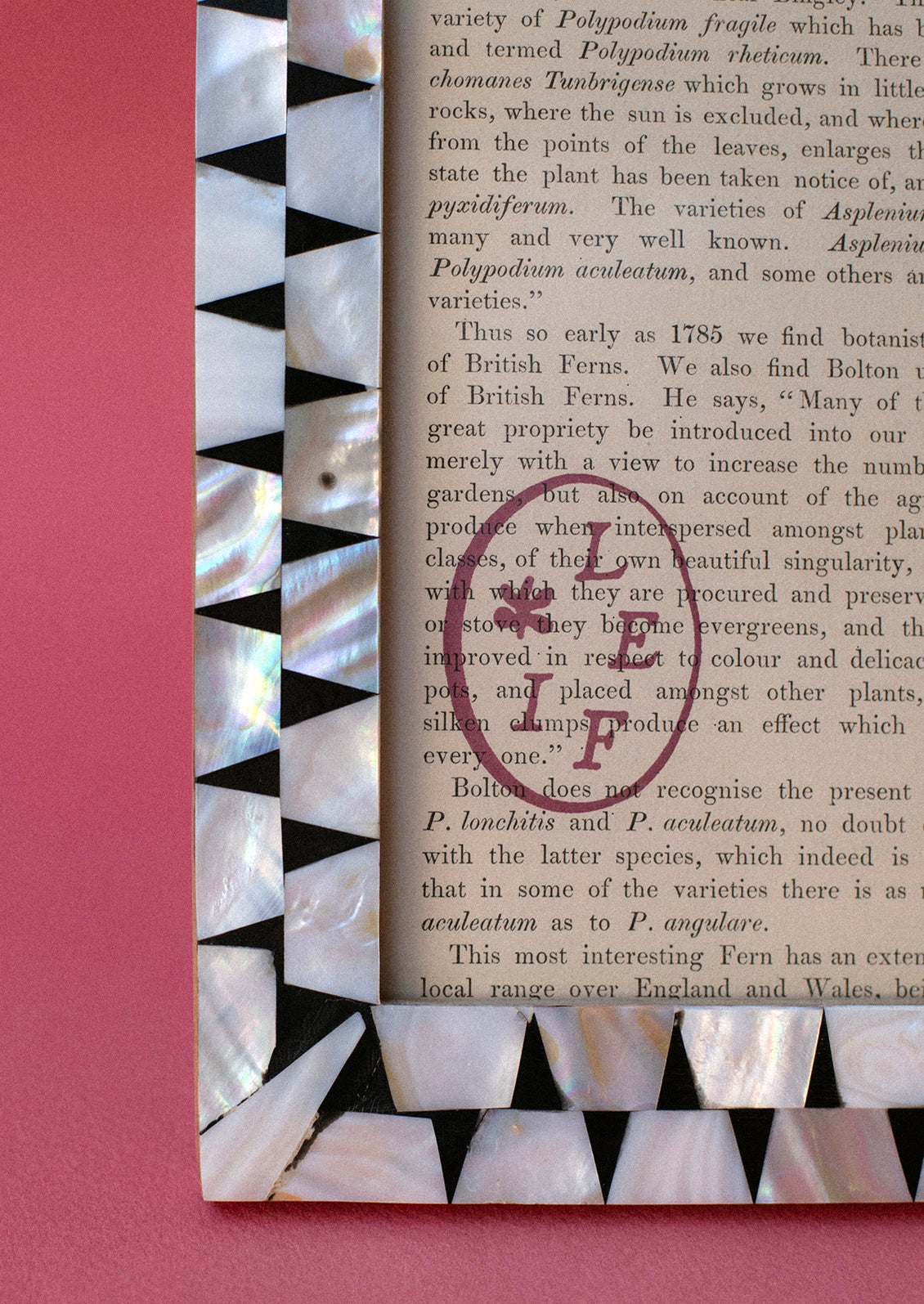 A black picture frame with geometric mother of pearl inlay.