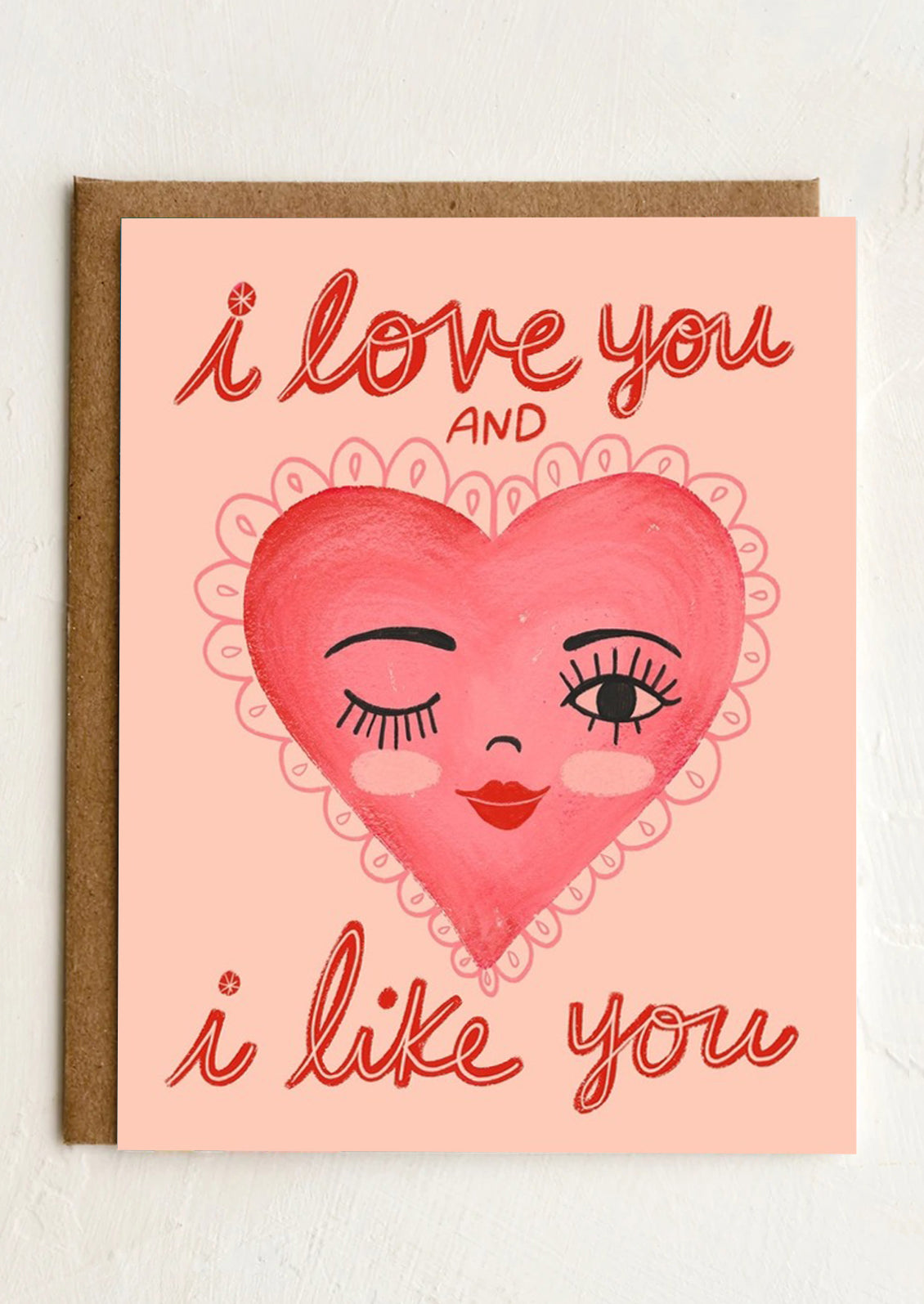 A greeting card with illustration of a heart with a human face, text reads "I love you and I like you".