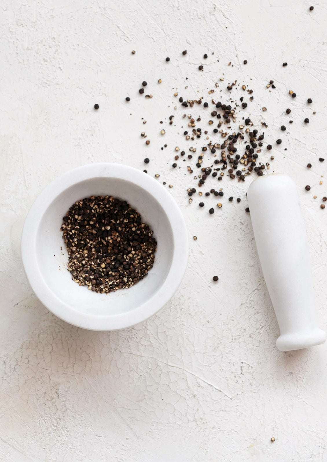 A mortar and pestle in solid white marble.